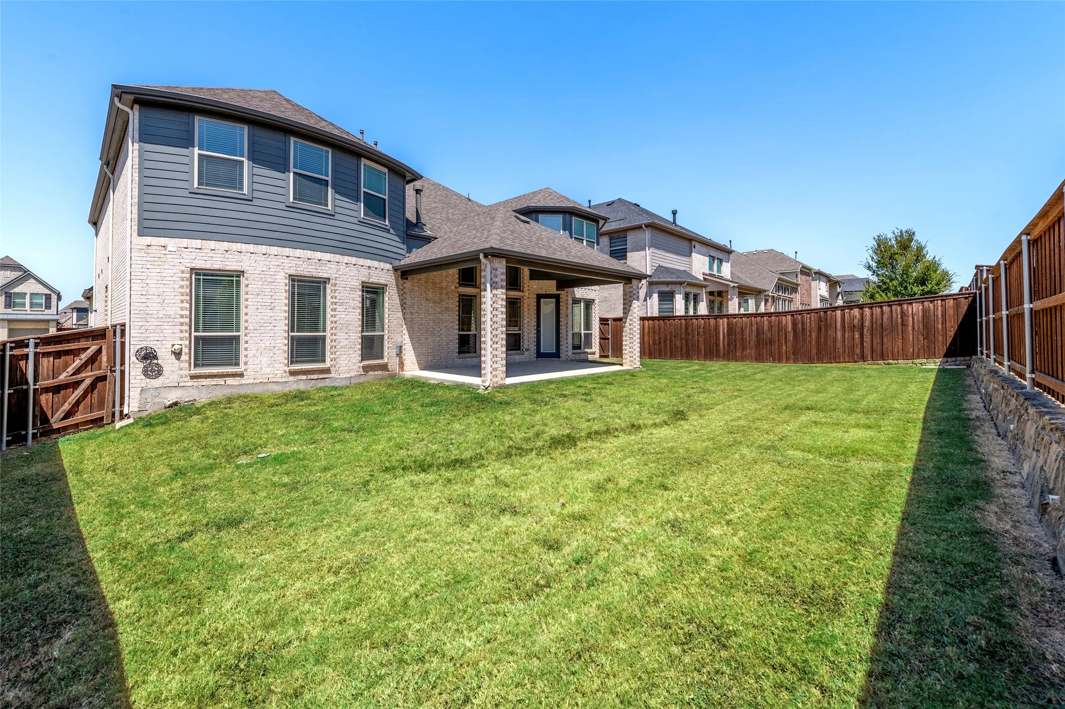 Expansive backyard featuring a covered patio, manicured lawn, and privacy fencing