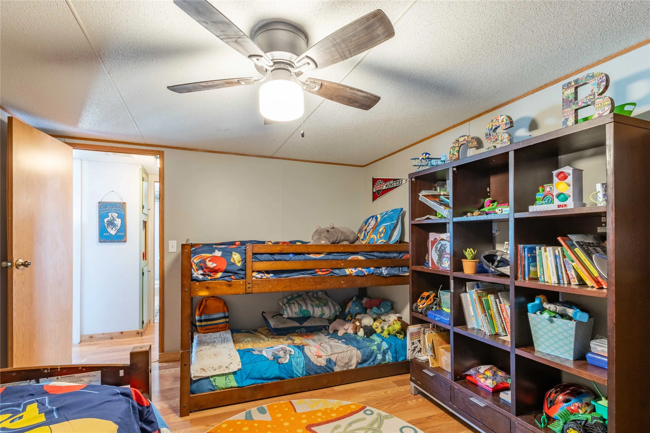 Wood-finish flooring with a ceiling fan light fixture, built-in shelving, and a wood-finish bunk bed frame