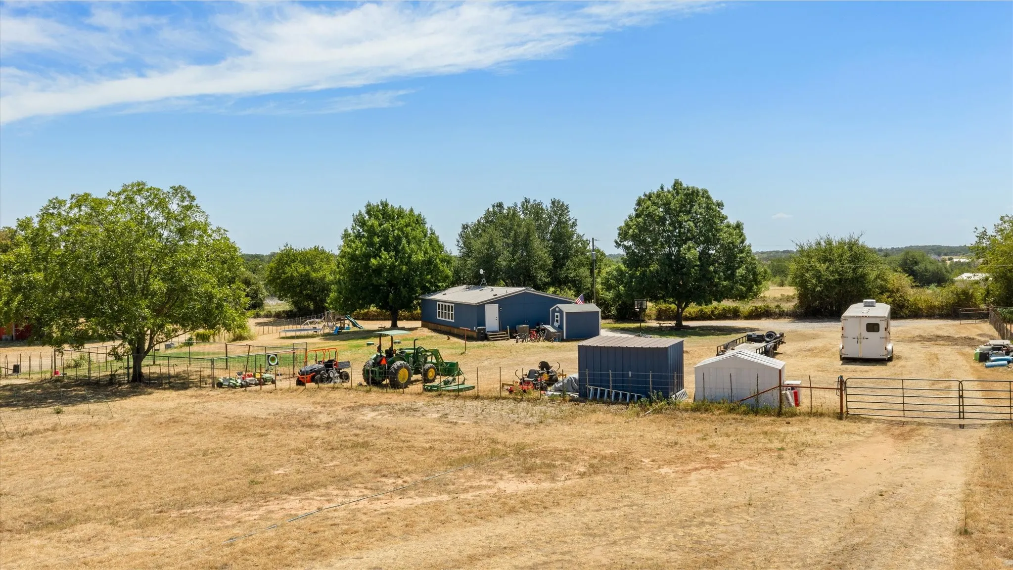 Expansive property featuring a detached structure, multiple storage sheds, and a substantial gated entry