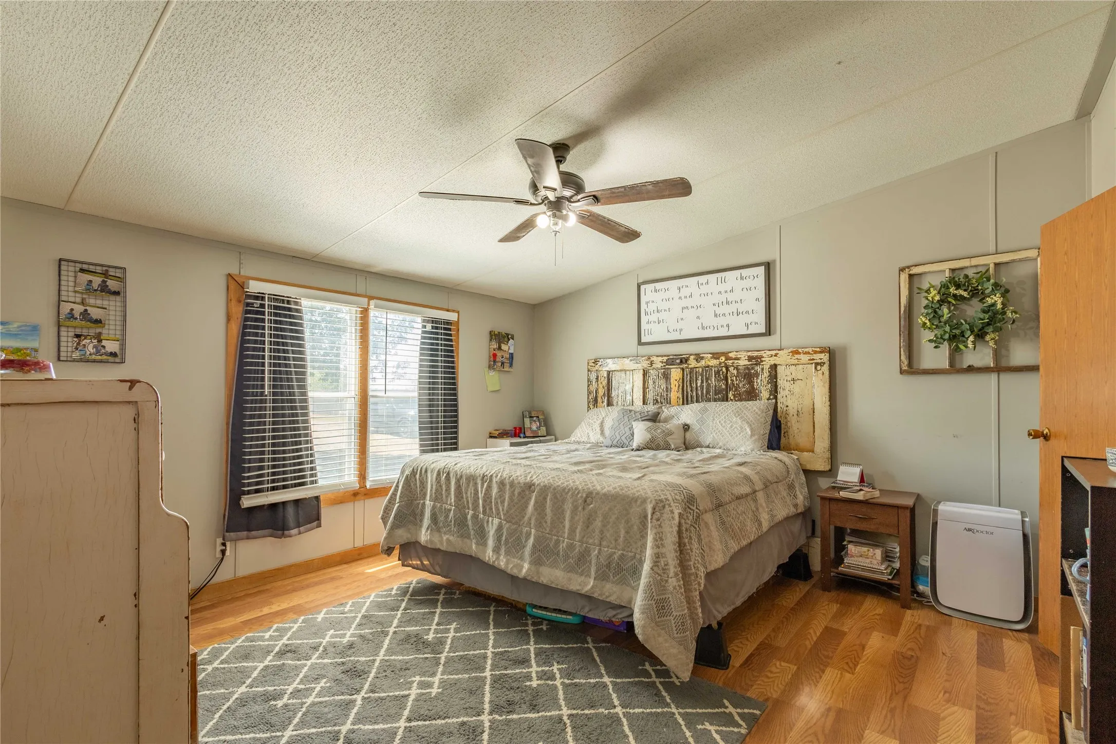 Wood-finish flooring, ceiling fan with light fixture, and windows with blinds