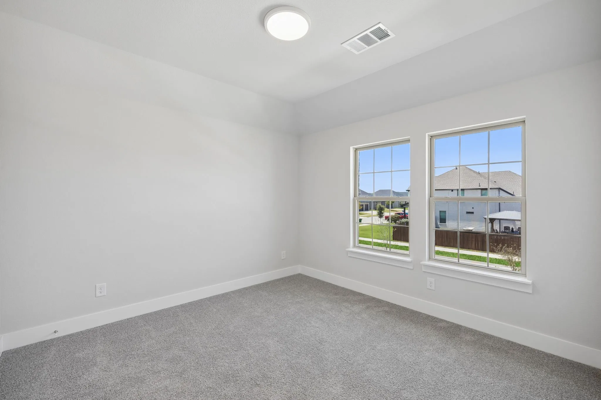 Recessed ceiling, neutral wall paint, two double-hung windows, carpeted flooring, and a flush-mount ceiling light
