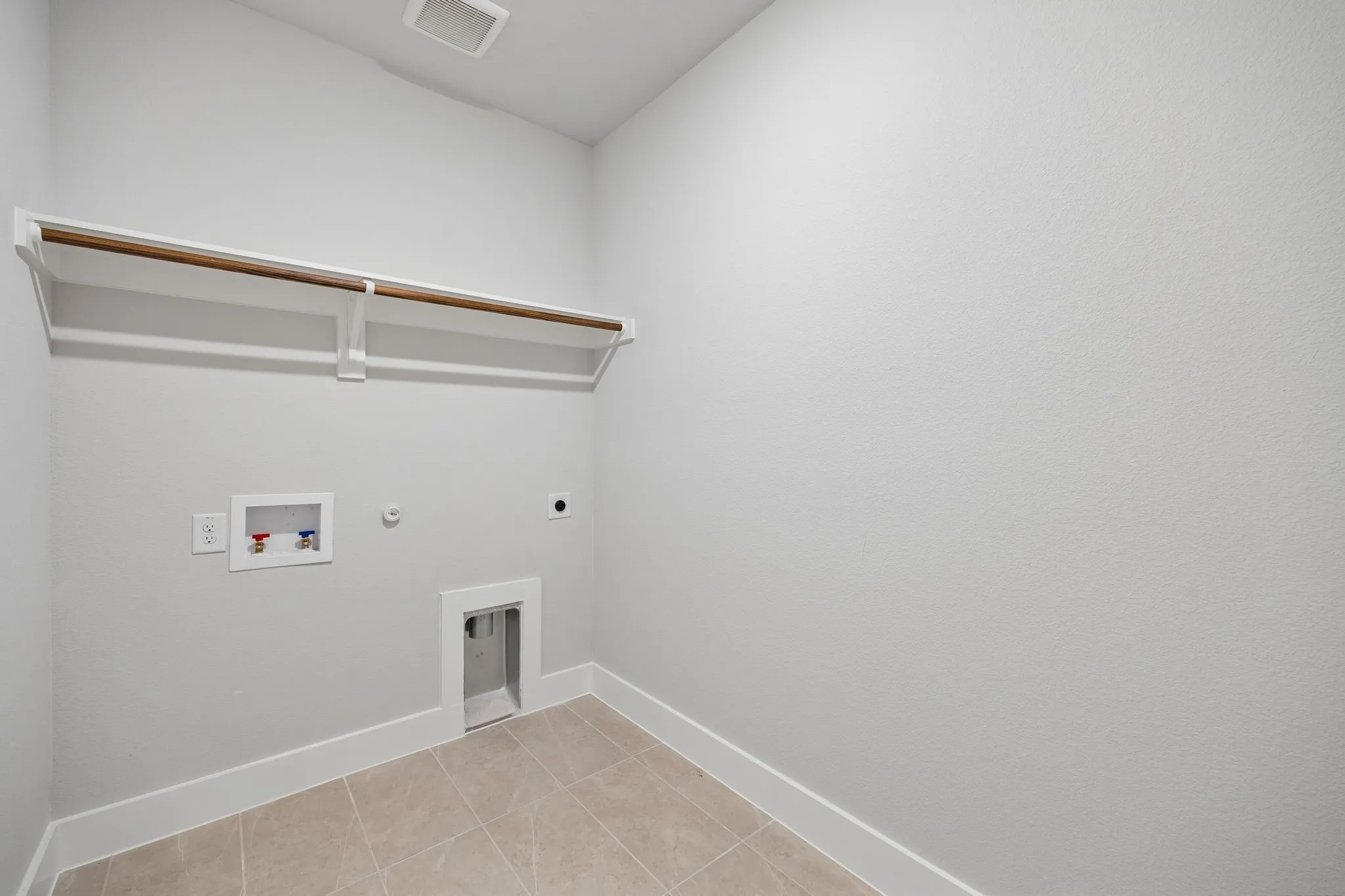 Utility room with tile flooring, wall-mounted shelving, and plumbing hookups
