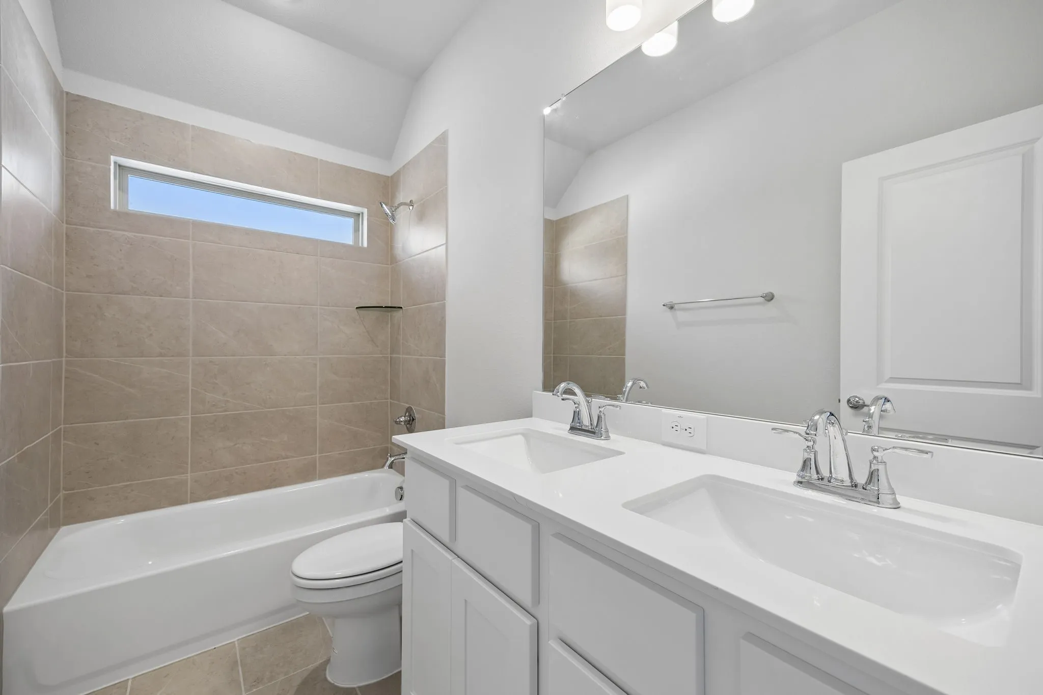 Spa-inspired primary bathroom featuring dual vanities with white cabinetry, white quartz countertops, and polished chrome faucetry
