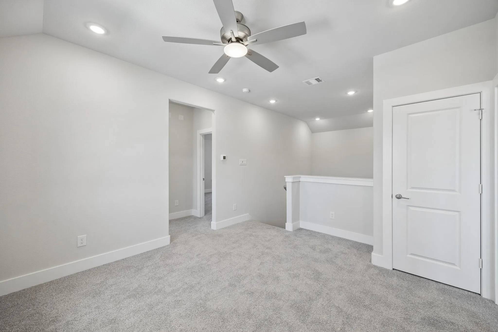 Recessed lighting, ceiling fan with brushed nickel finish, plush carpeting, white interior doors, and a partial wall with railing