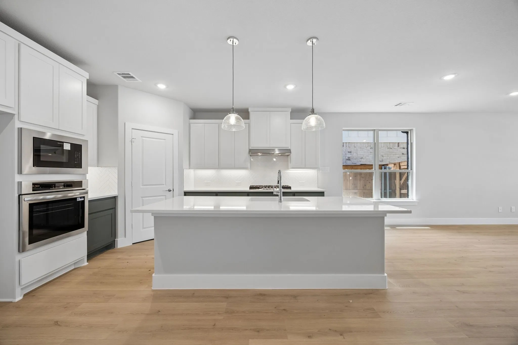 Kitchen featuring a central island, recessed lighting, stainless steel appliances, pendant lighting, and wood-finish flooring