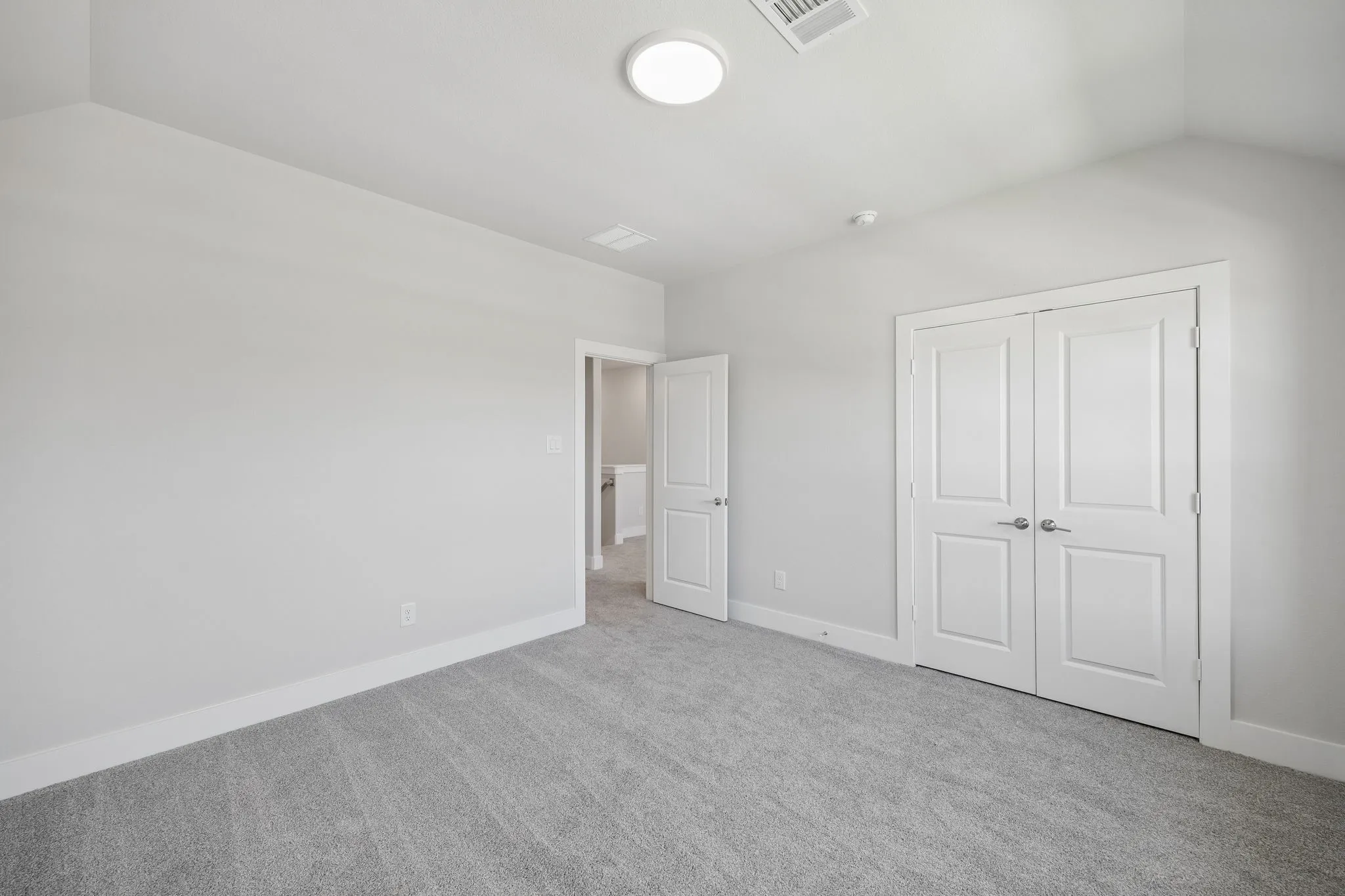 Neutral tone wall finishes, gray carpet flooring, white trim, recessed lighting, and a vaulted ceiling