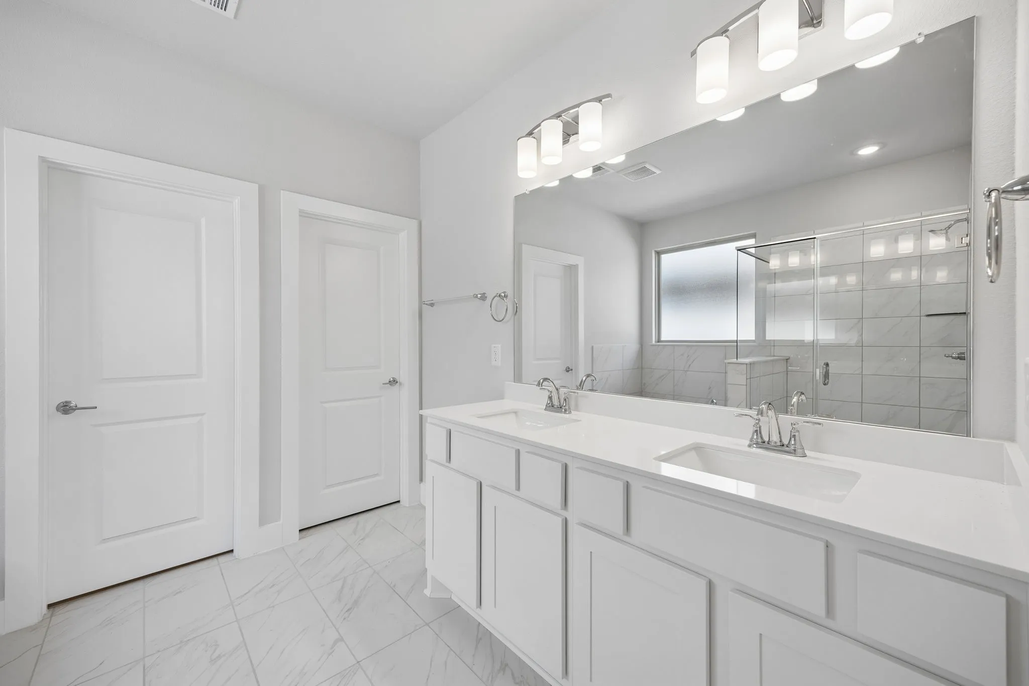 Double vanity with white cabinetry, polished chrome fixtures, and a large mirror