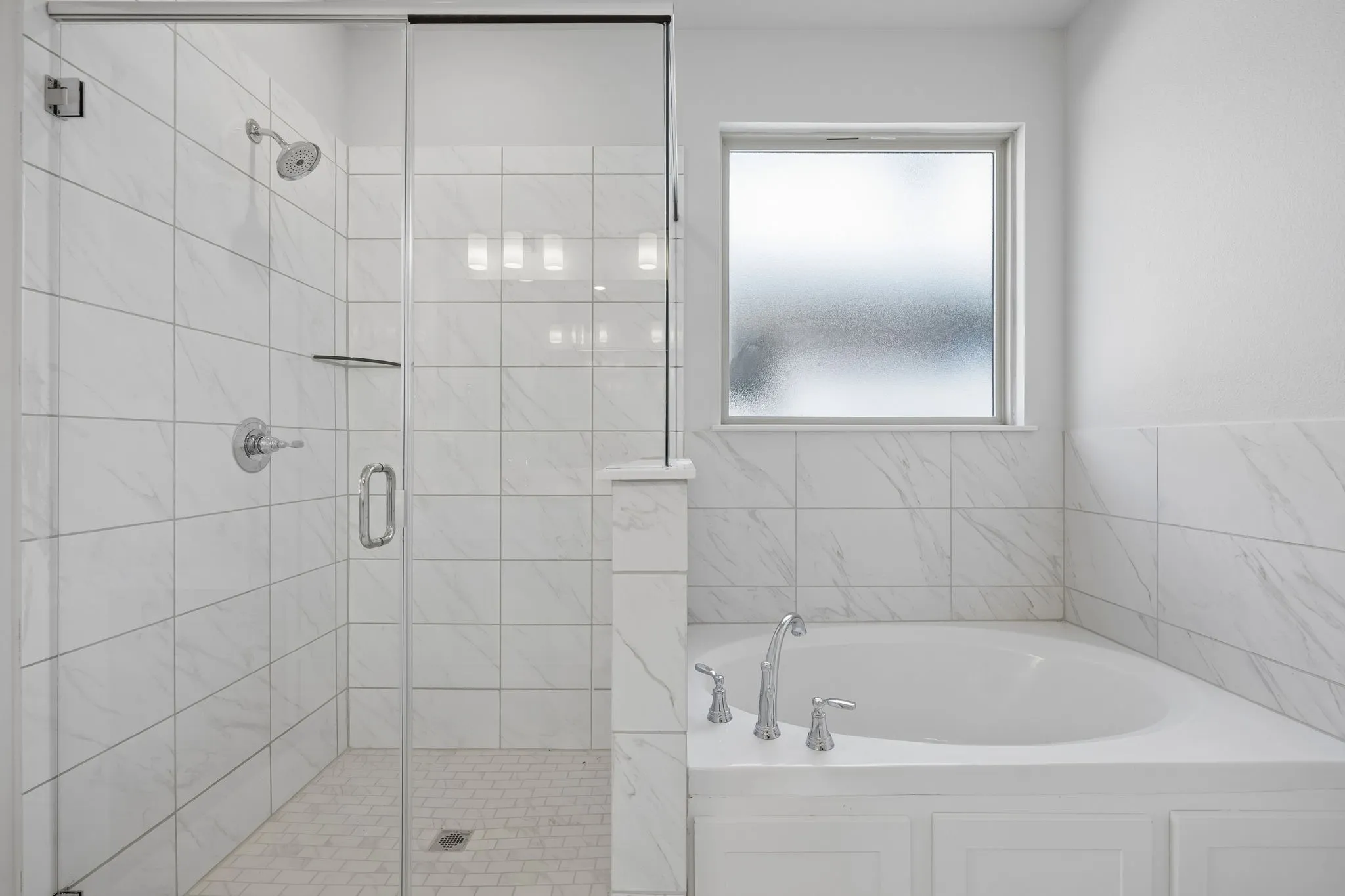 Walk-in shower with clear glass enclosure, white tile surround, and chrome fixtures