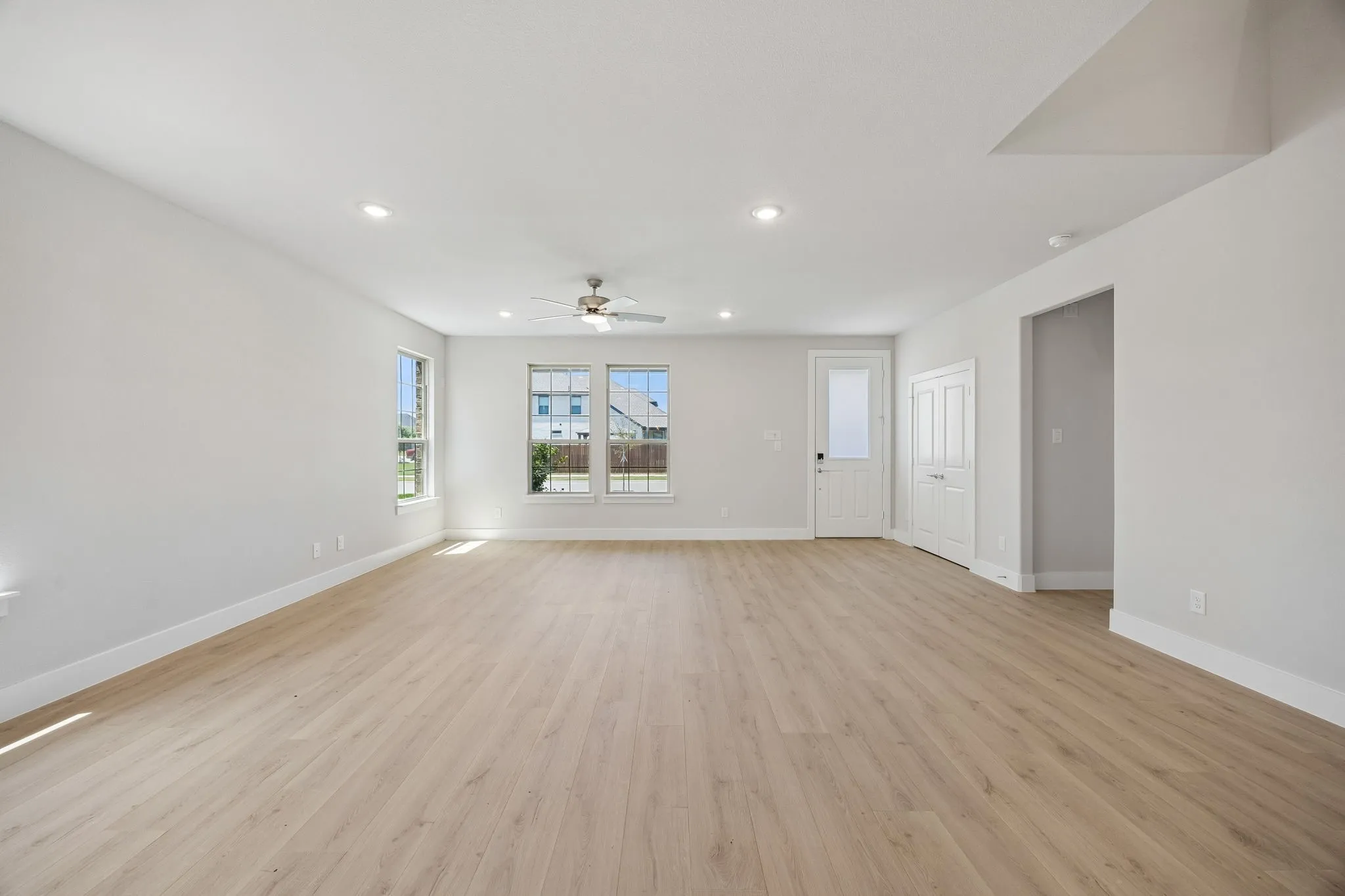 Spacious room featuring light wood-finish flooring, recessed lighting, and a ceiling fan