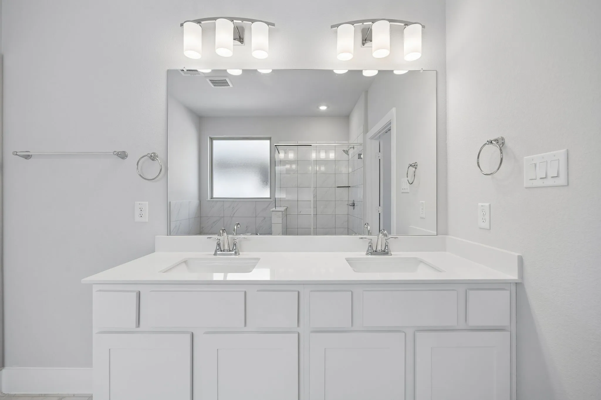 Dual vanity with undermount sinks, quartz countertops, white cabinetry, and brushed nickel fixtures