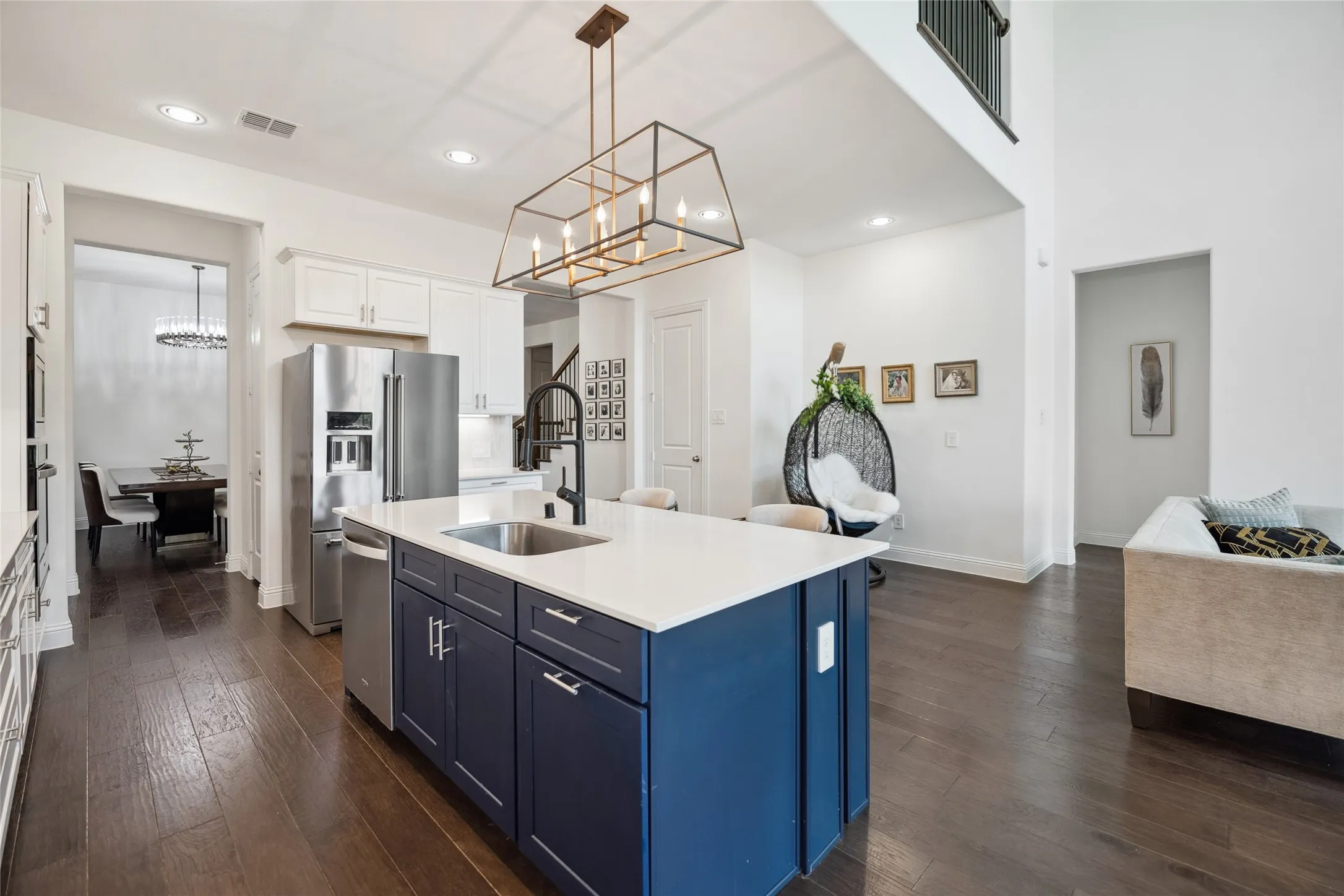 Gourmet kitchen with a large island, white countertops, dark blue cabinetry, stainless steel appliances, and a modern rectangular chandelier