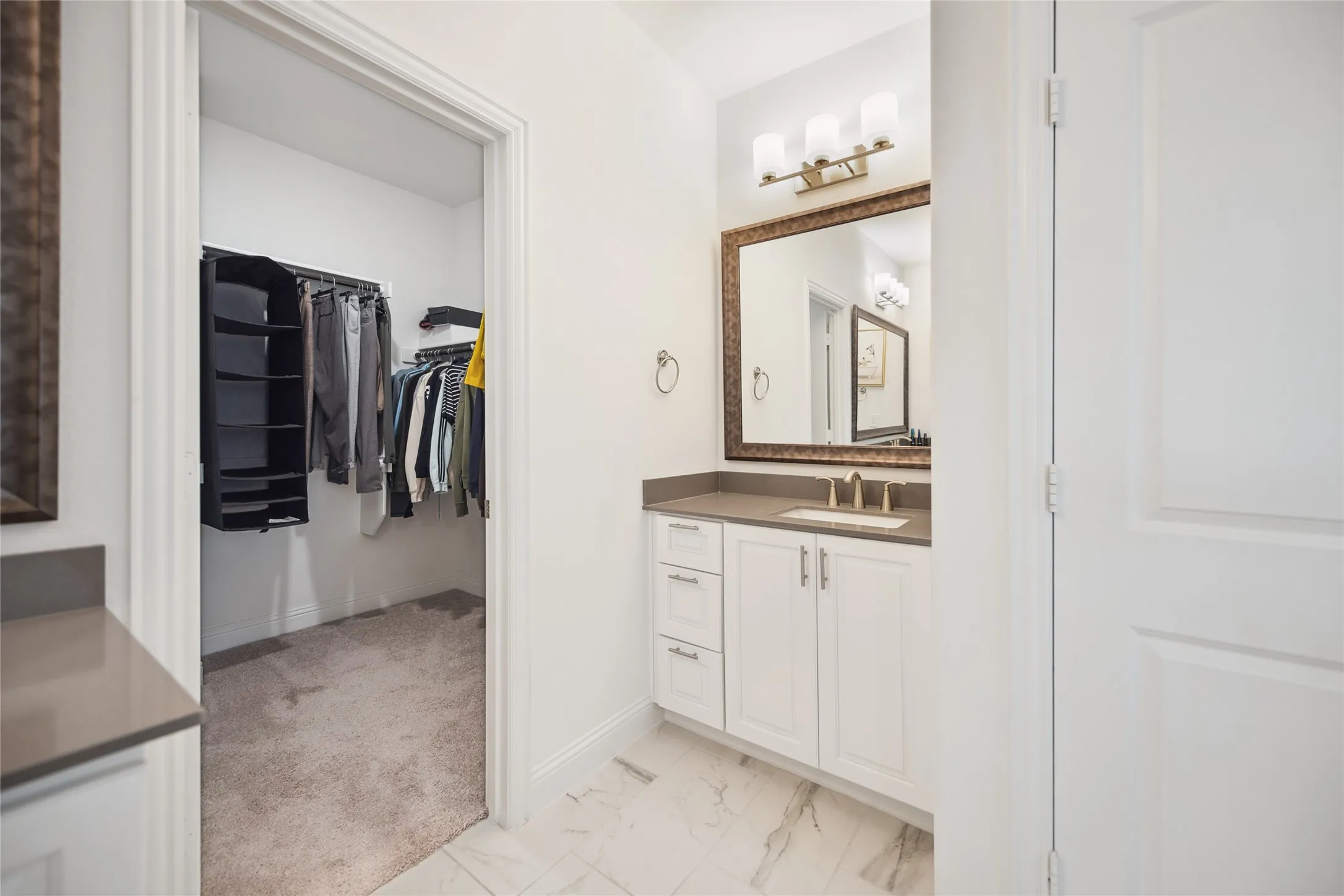 White vanity with a neutral-toned countertop and an undermount sink