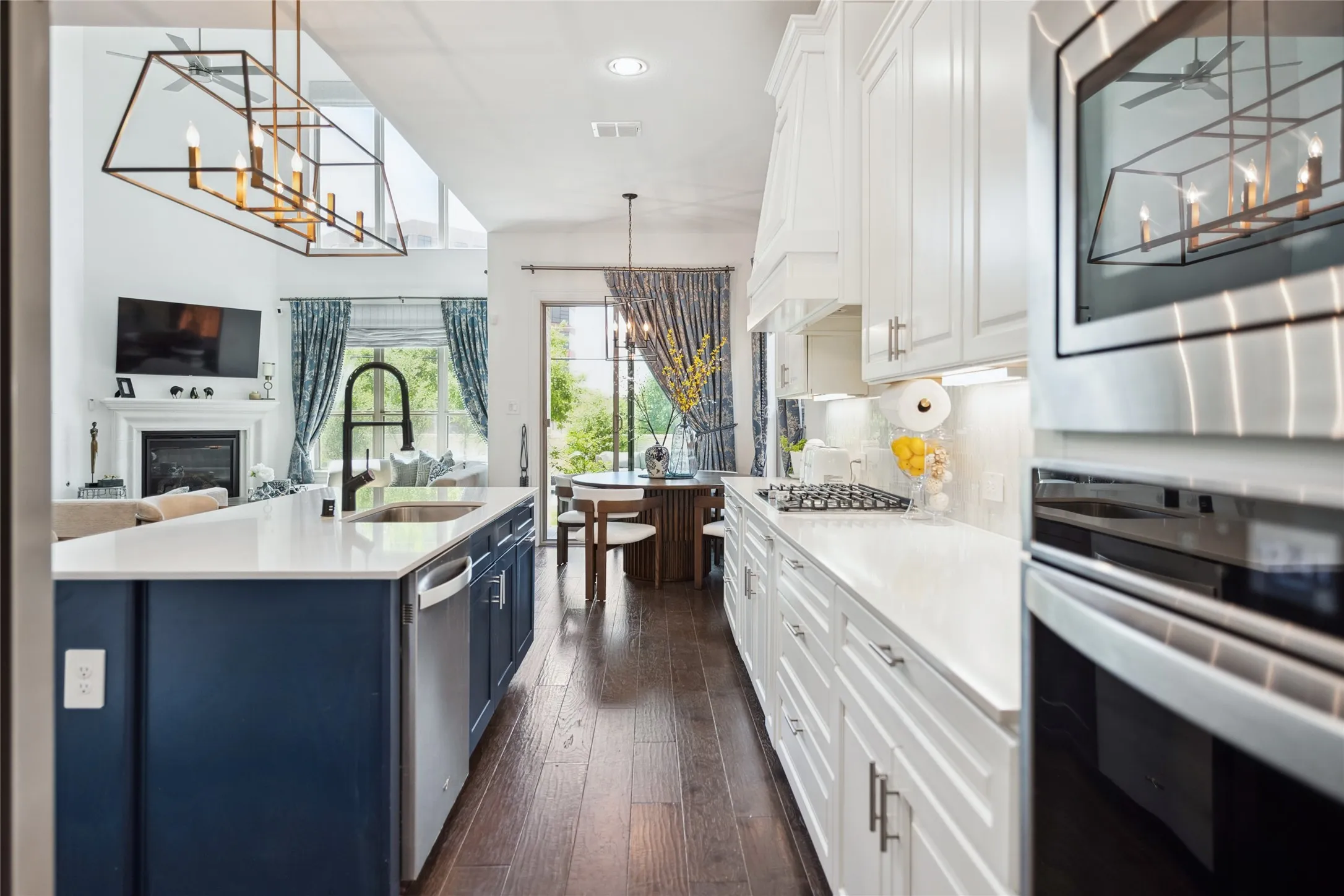 Kitchen featuring a large island with sink, stainless steel appliances, white cabinetry, and wood-finish flooring