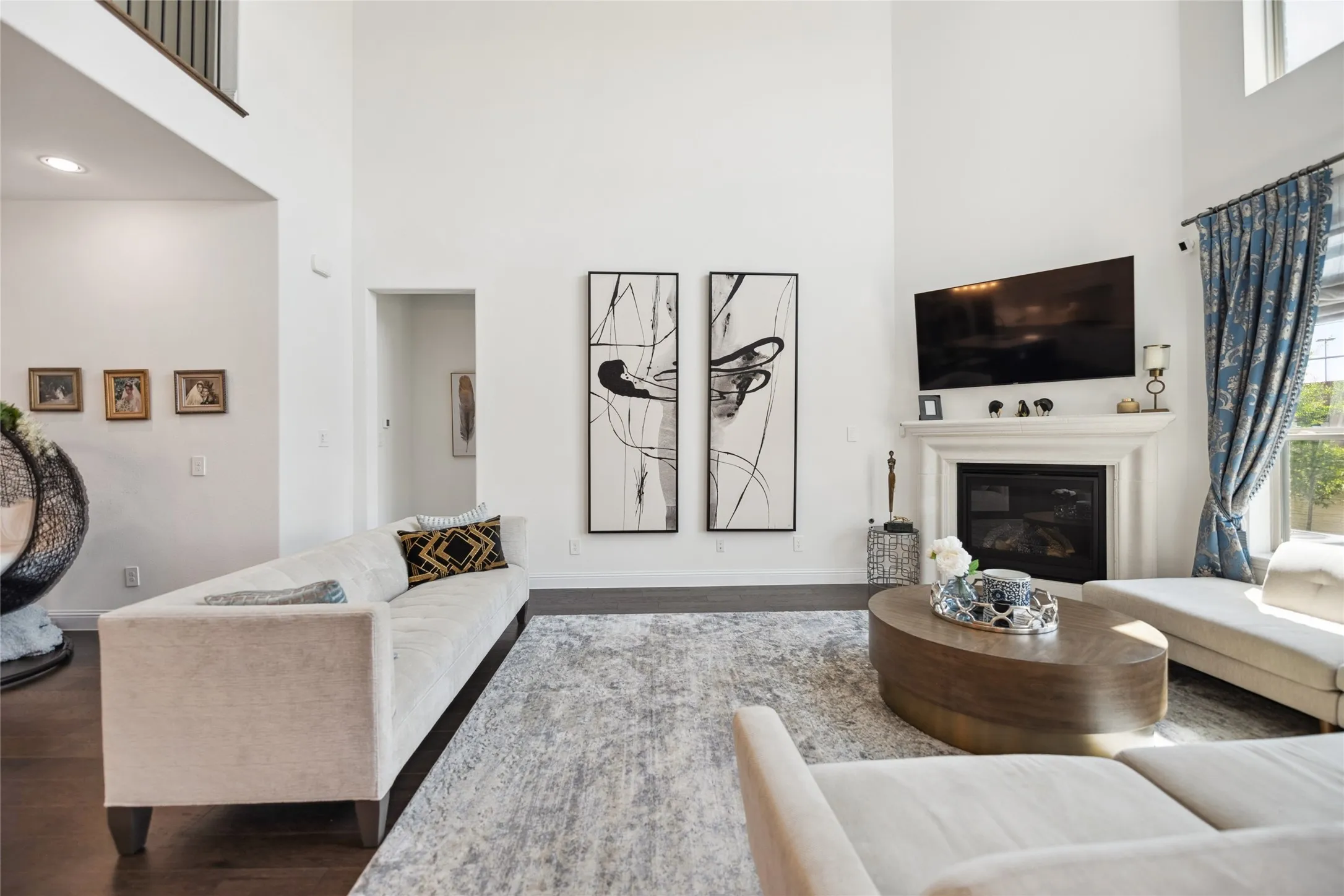 Two-story living area featuring a fireplace with a detailed mantel, dark wood-finish flooring, and recessed lighting