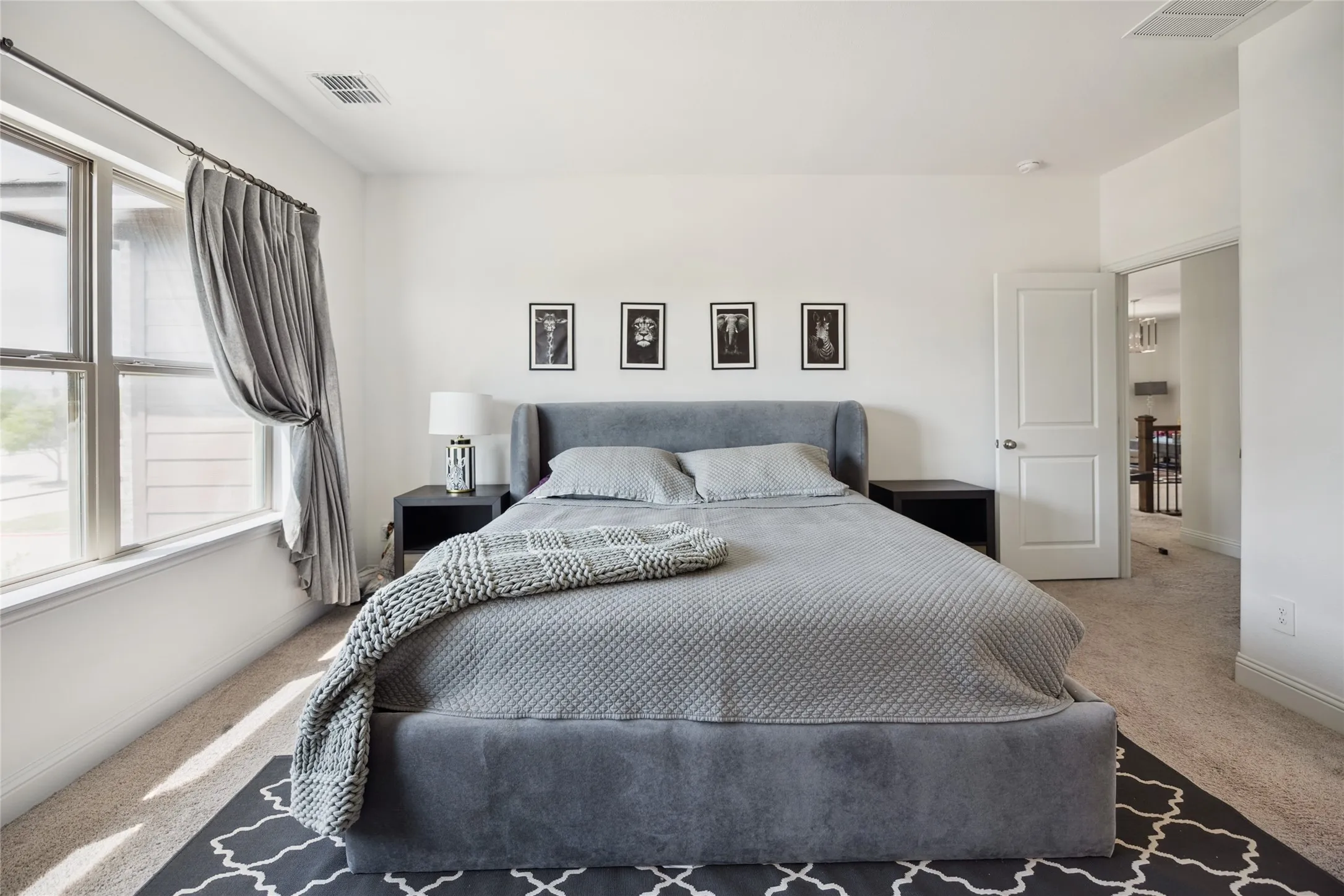 Carpeted bedroom featuring a large window, white walls, and a paneled door