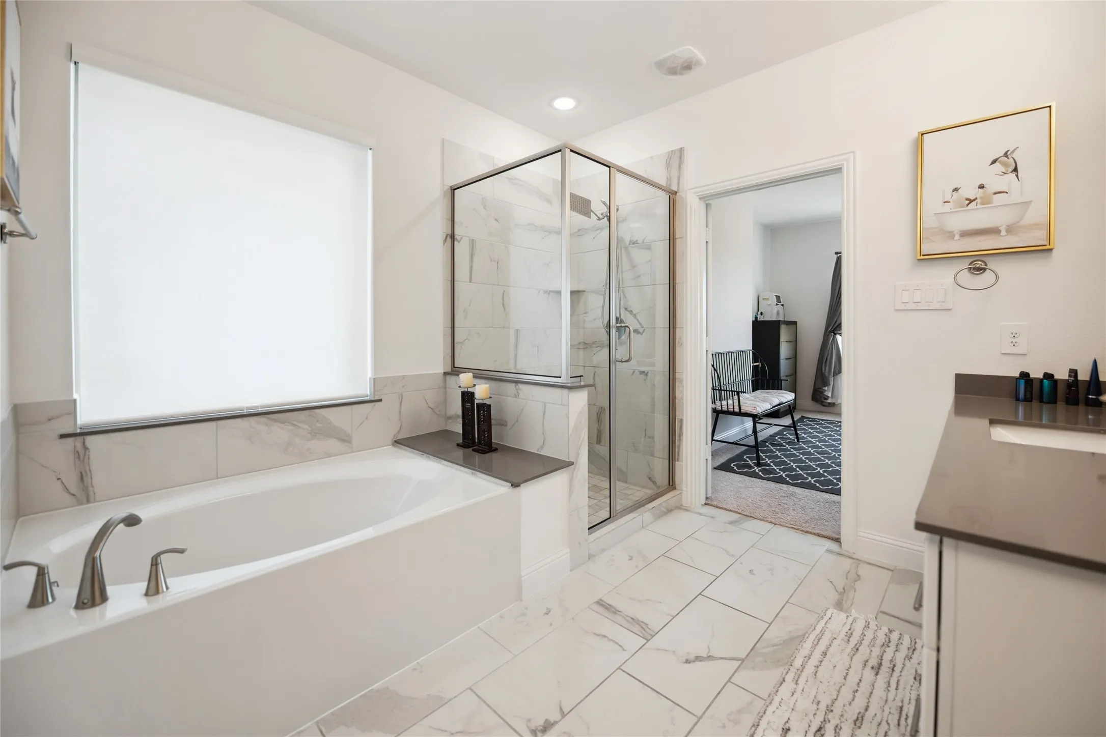 Bathtub with deck-mounted brushed nickel fixtures, glass-enclosed shower with tiled walls, and vanity with integrated sink and dark countertop