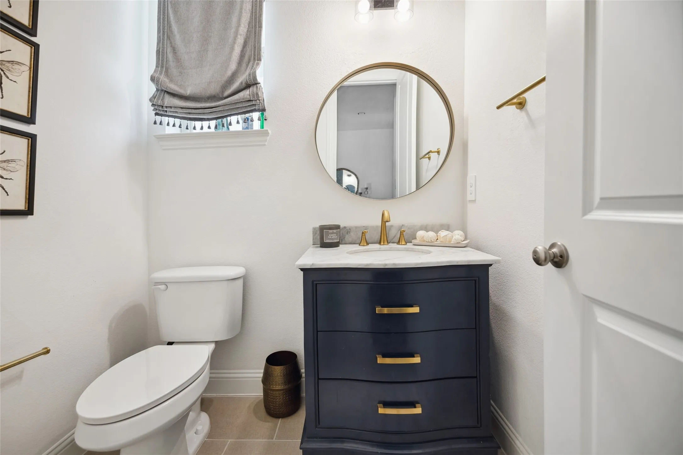 Vanity with a marble countertop, undermount sink, and brass-tone hardware