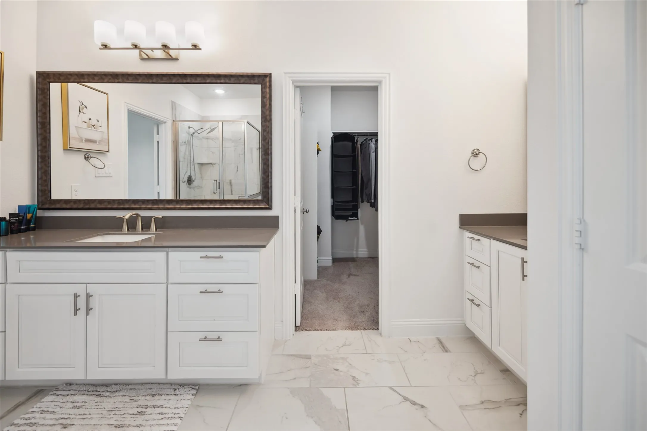 Dual vanity with white cabinetry and dark countertops