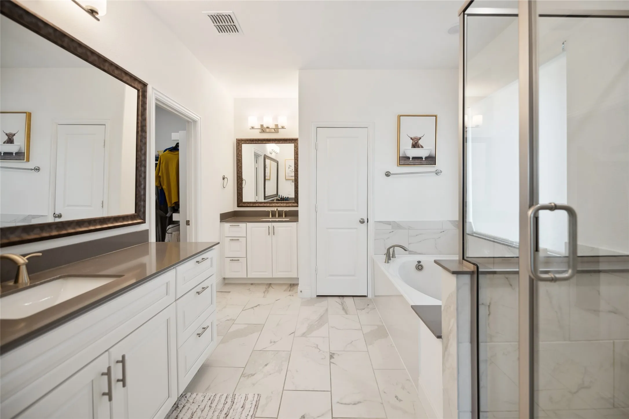 Dual vanity with undermount sinks, built-in soaking tub, glass-enclosed shower, tile flooring, and wall-mounted light fixtures