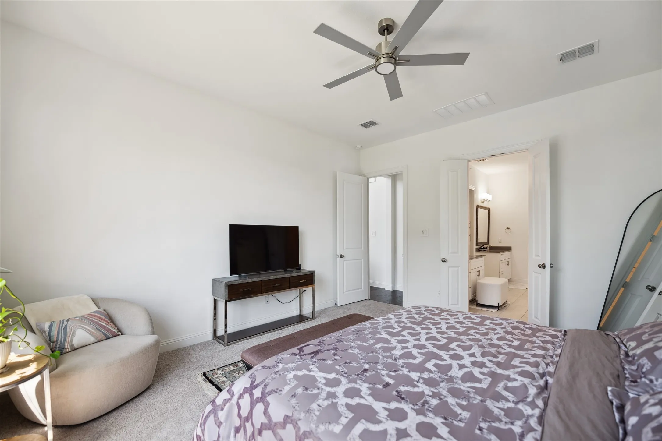 Recessed lighting, ceiling fan, carpeting, and double doors opening to an attached bathroom