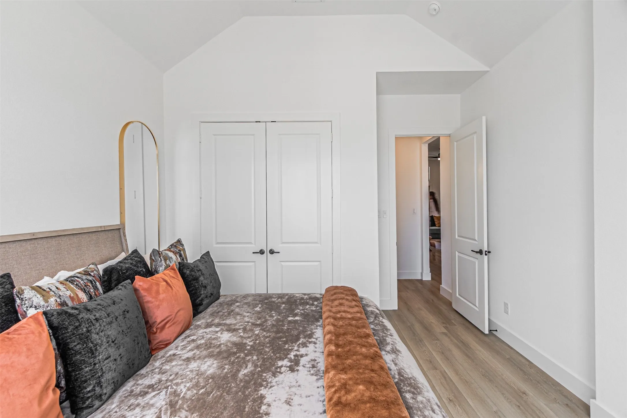 Vaulted ceiling, double closet doors, contemporary black hardware, wood-finish flooring, and recessed lighting
