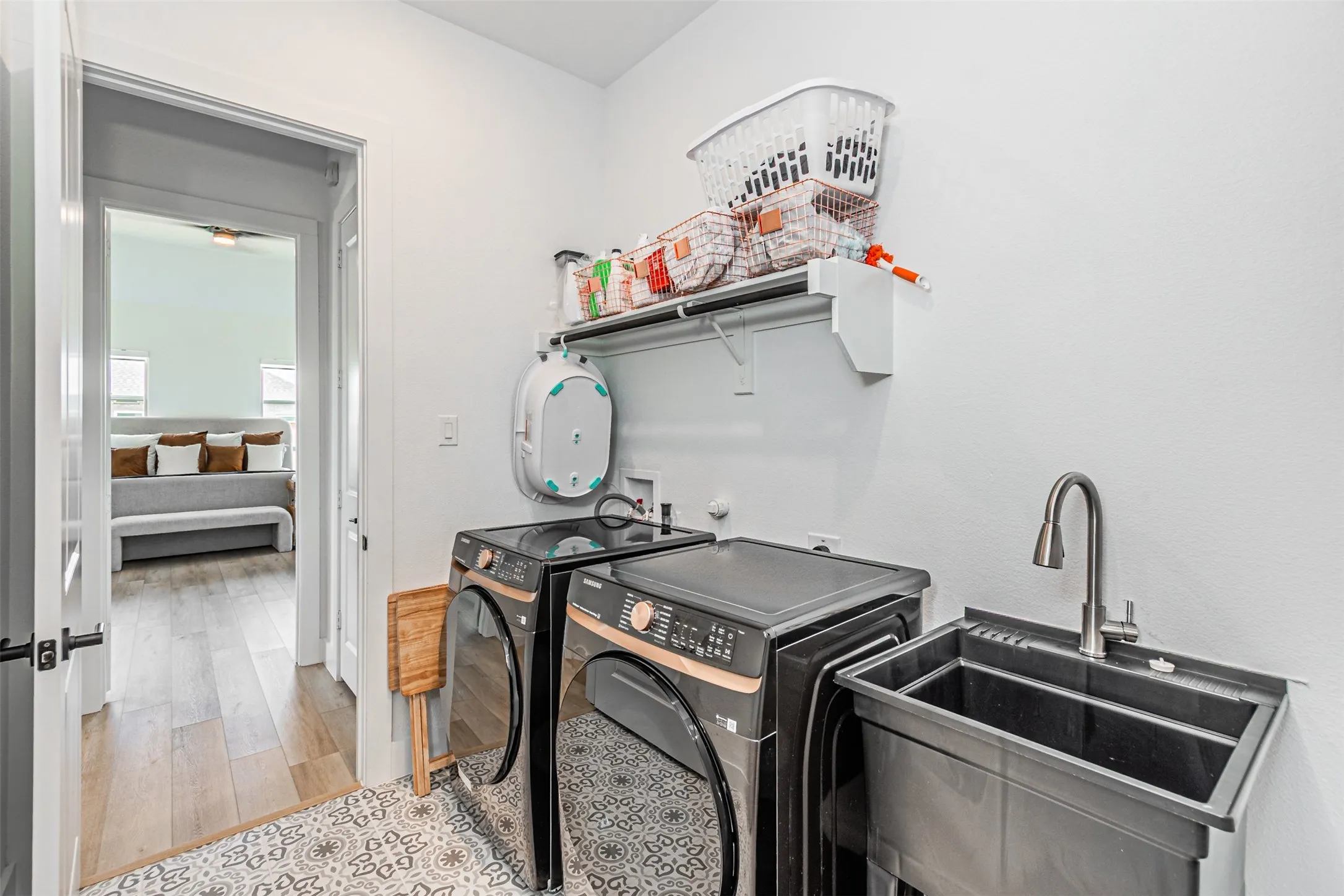 Dedicated utility space featuring a laundry sink with a gooseneck faucet and an overhead storage shelf