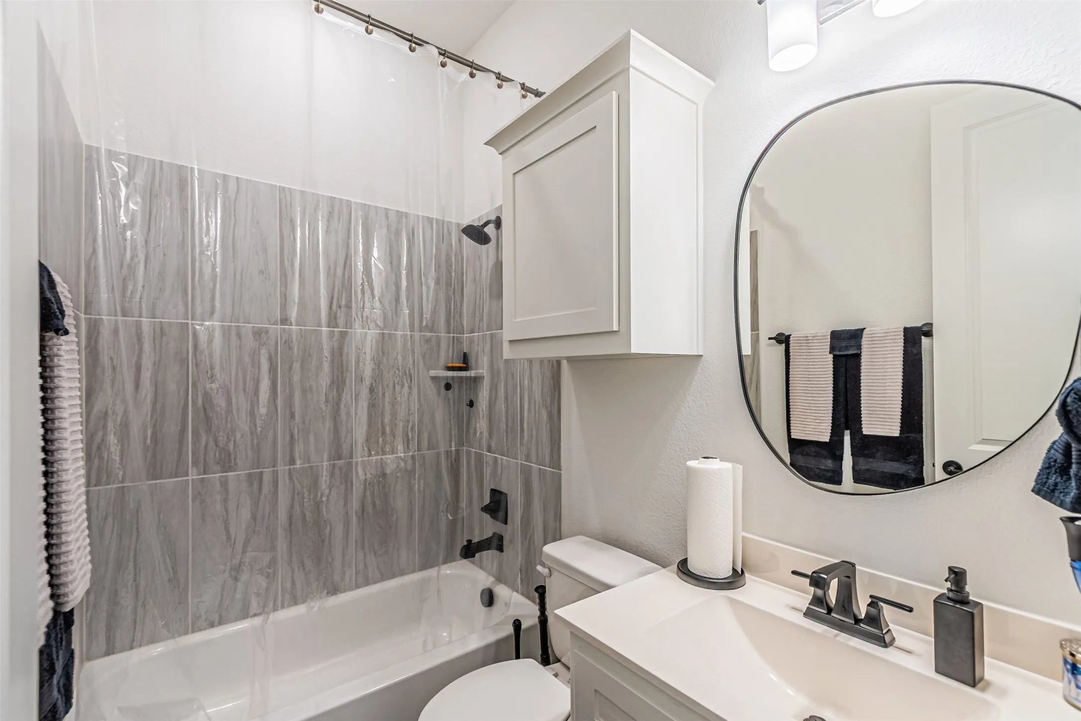 White vanity with integrated sink, black-finish faucet, and coordinating oval mirror