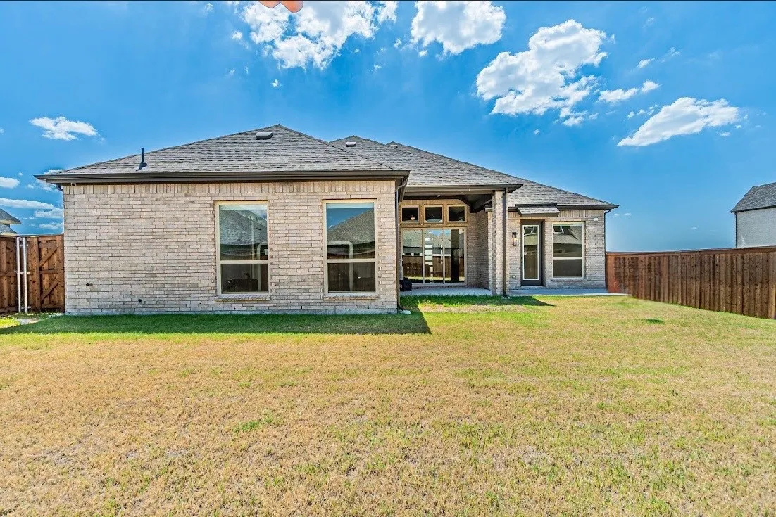 Brick exterior with multiple windows, a covered patio, and a private fenced yard