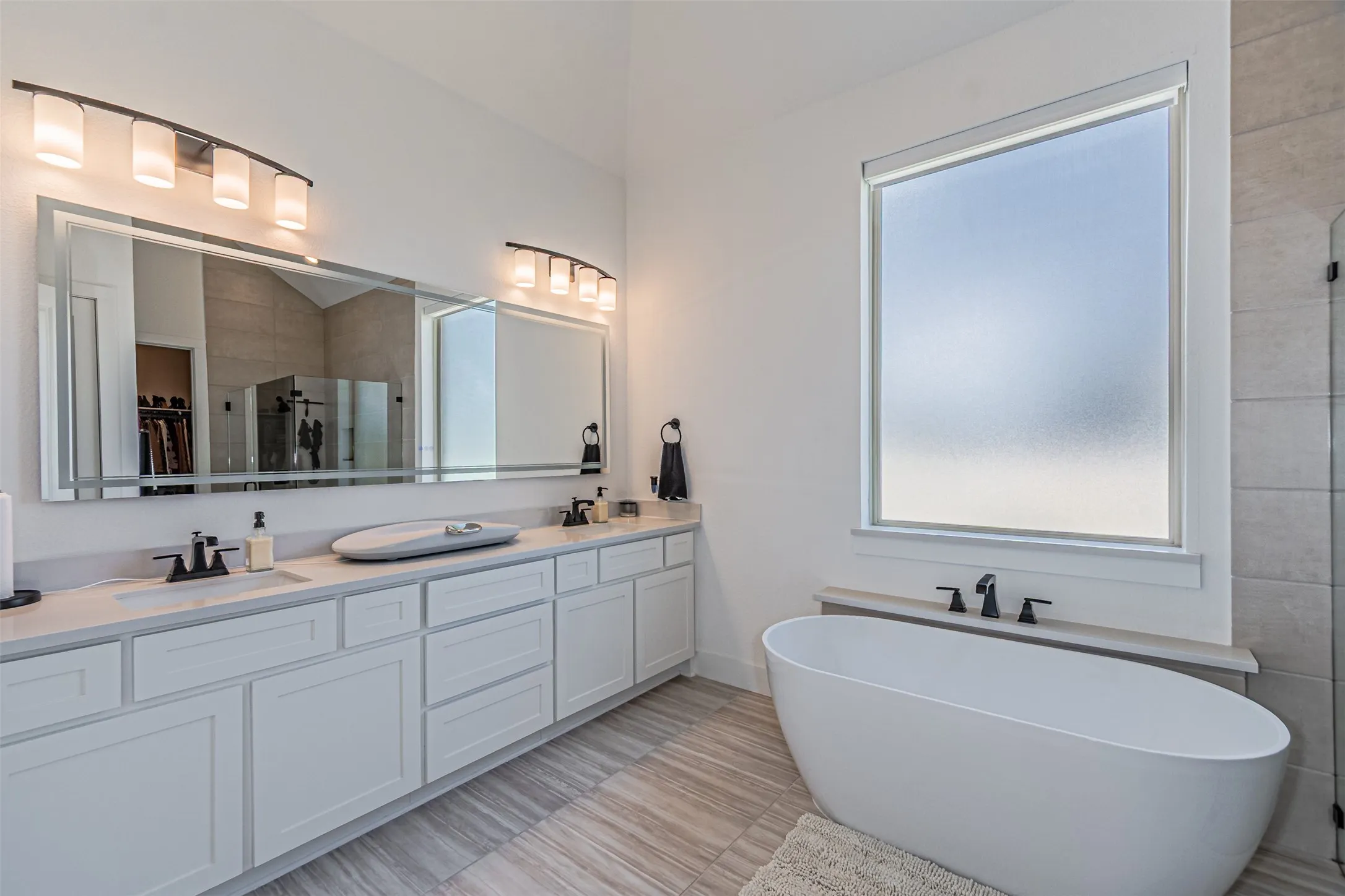 Dual vanity with undermount sinks, white cabinetry, and a large frameless mirror