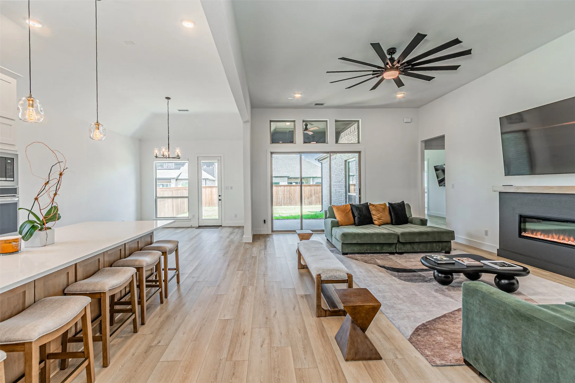 Open-concept living space with wood-finish flooring, a contemporary ceiling fan, and a built-in electric fireplace