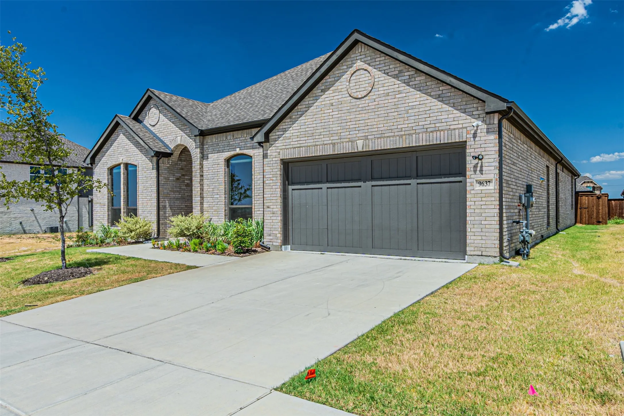 Light brick exterior with dark trim and a dark gray garage door
