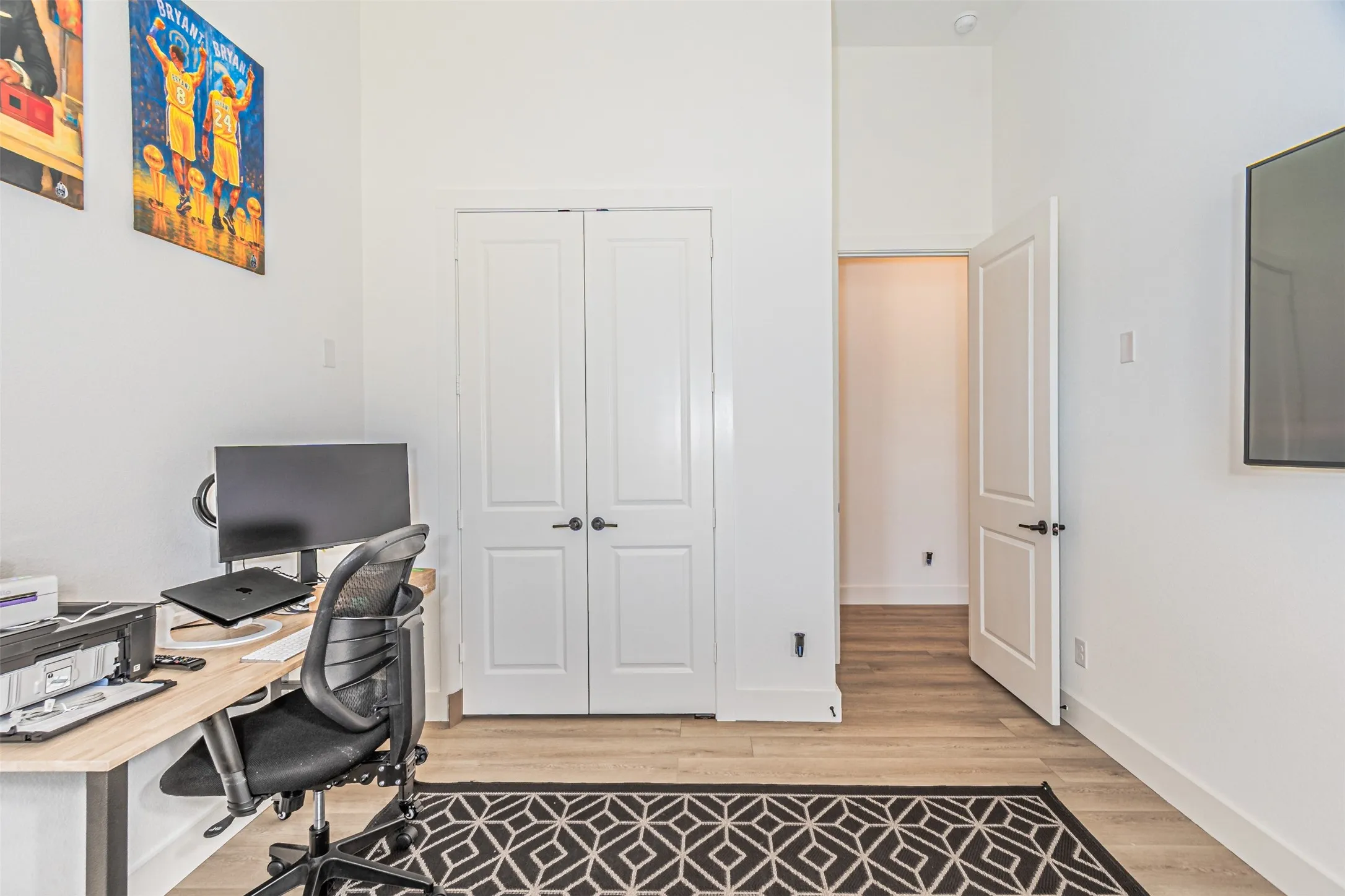Wood-finish flooring, white walls, and a white paneled door