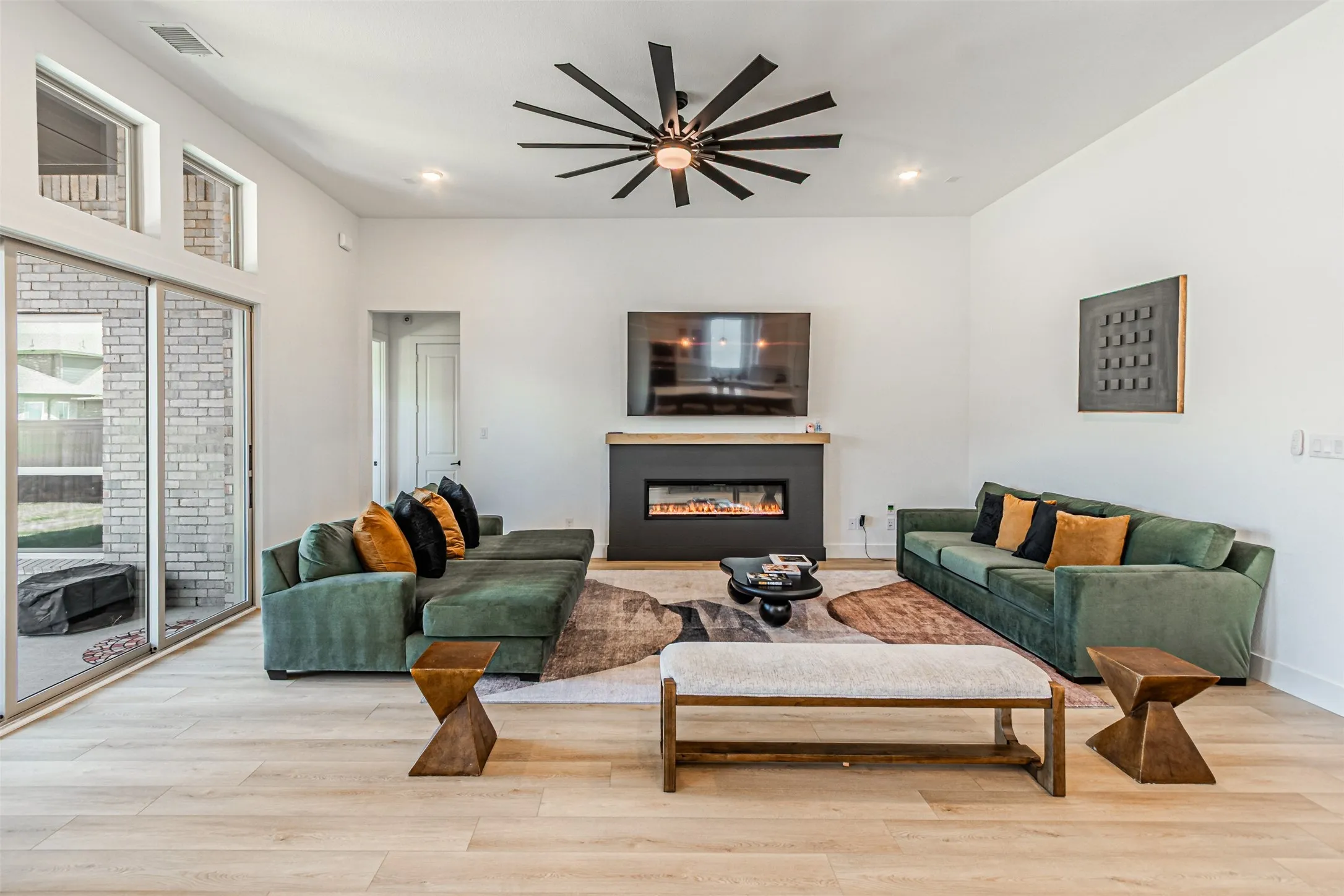 High ceilings with a modern ceiling fan, wood-finish flooring, and a fireplace with a wood mantle