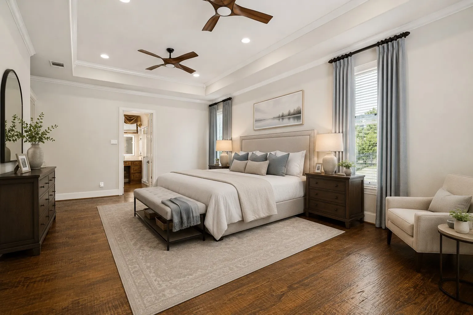 Spacious primary bedroom featuring hardwood flooring, a coffered ceiling with recessed lighting and ceiling fans, and dual nightstands with table lamps