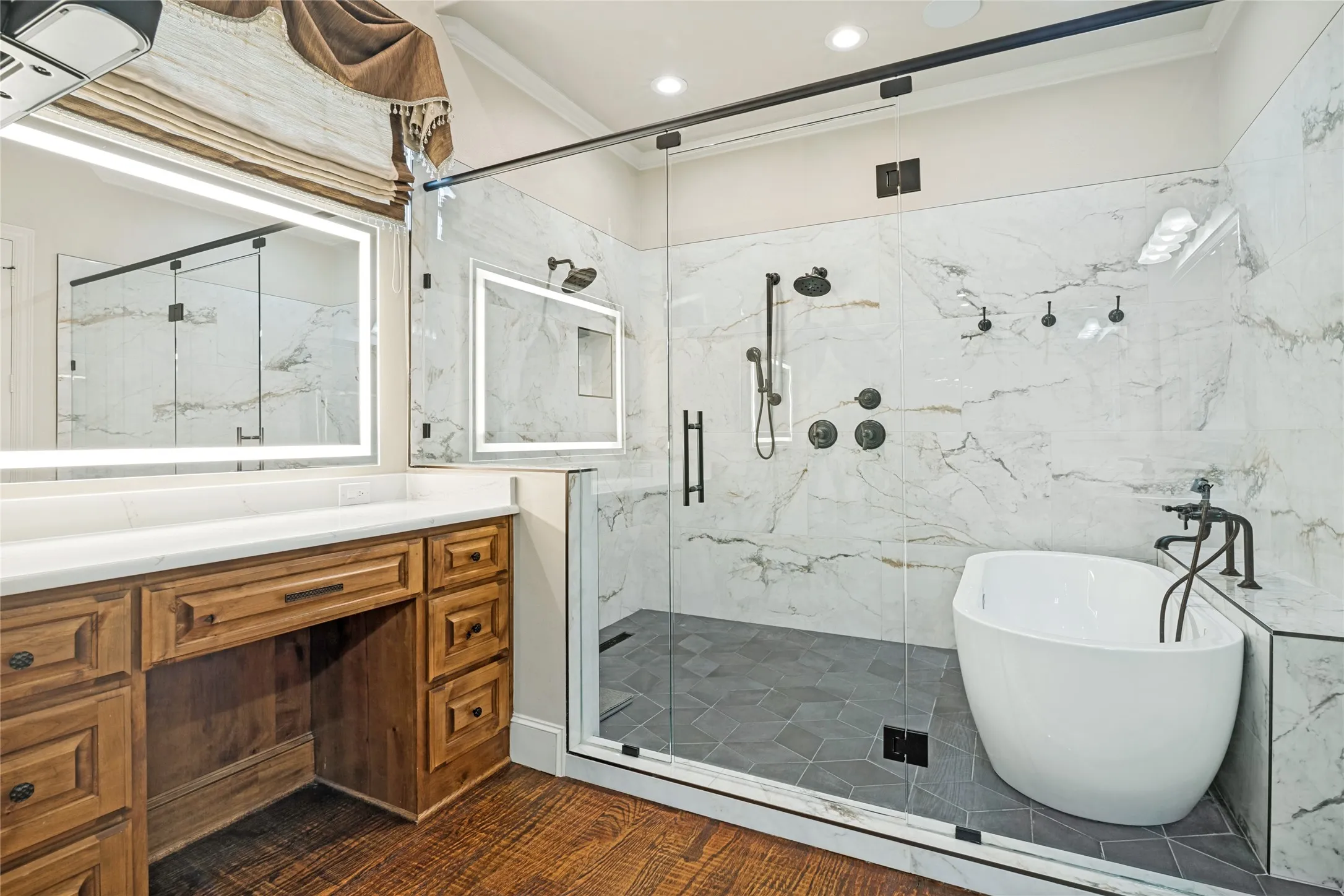 Hardwood-finish flooring leading to a freestanding tub and a spacious glass-enclosed shower with wall-mounted showerheads