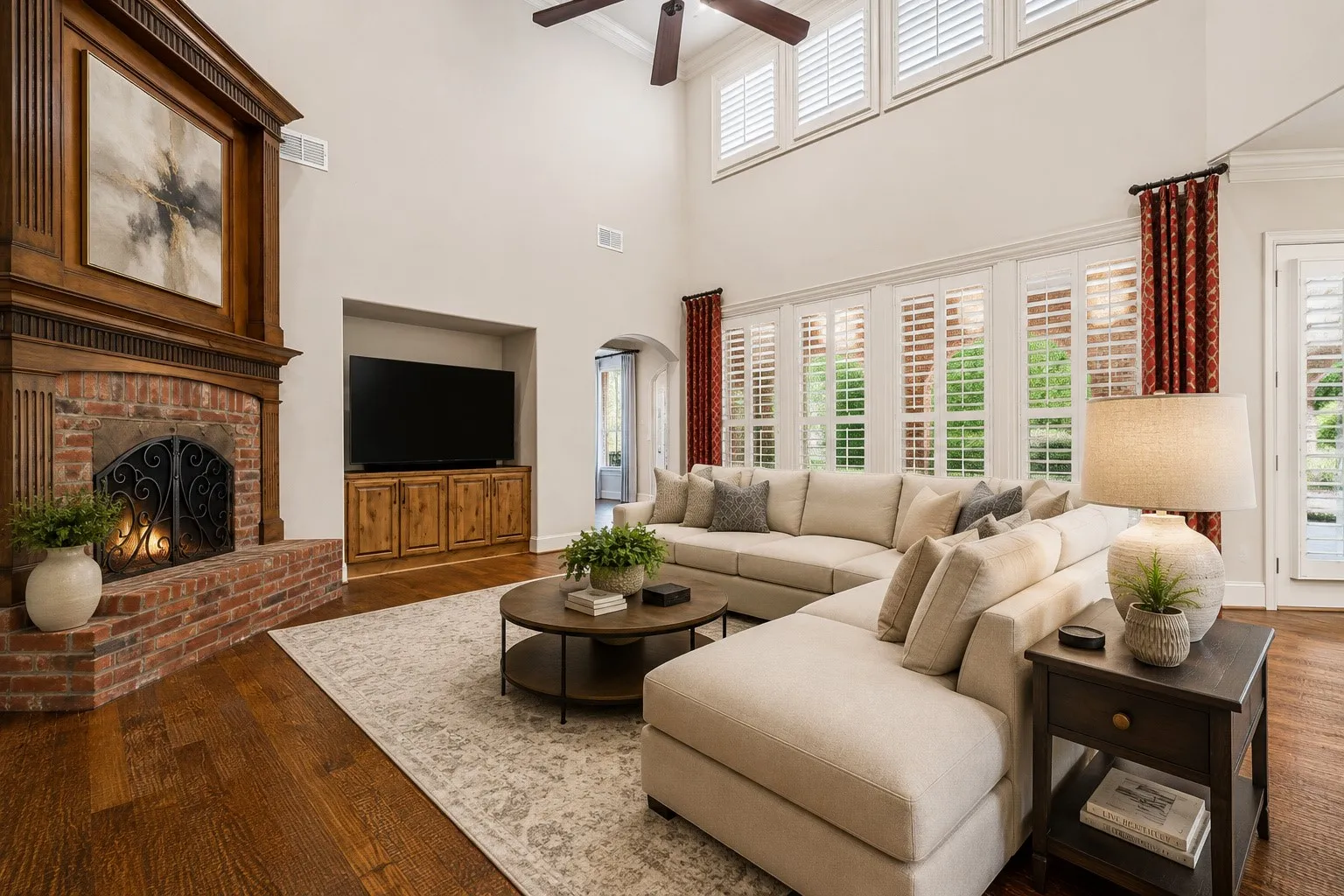 Two-story ceiling, hardwood flooring, brick fireplace with wood mantel, plantation shutters, and built-in media cabinet. virtual staged
