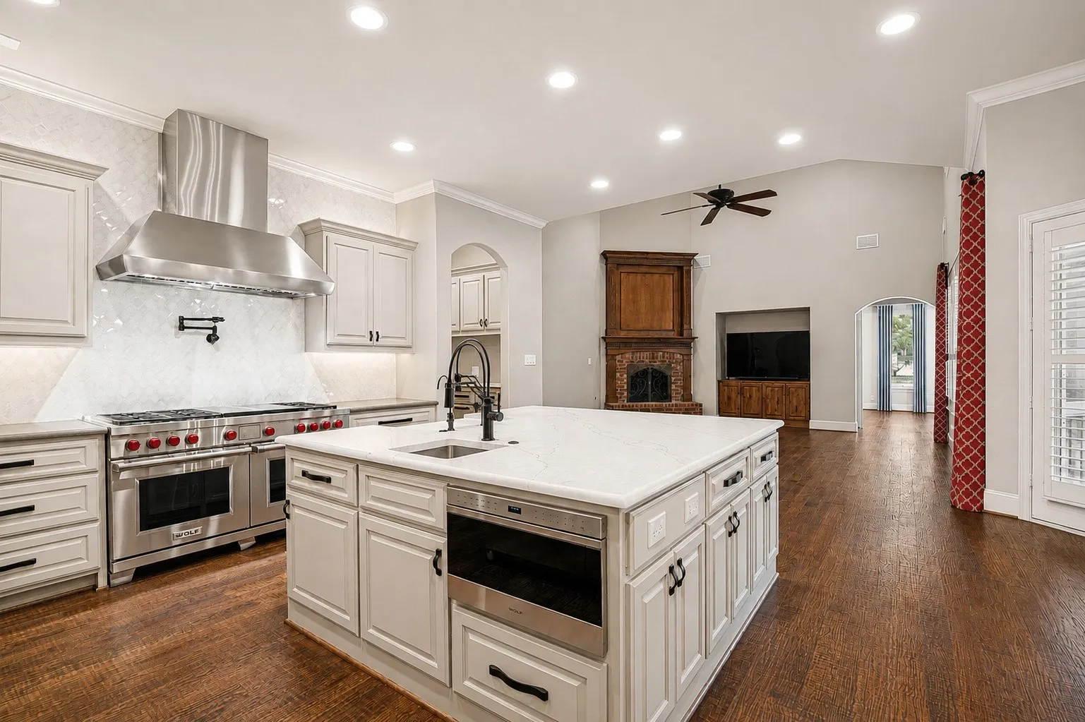 Gourmet kitchen with professional-grade stainless steel appliances, solid surface countertops, light-toned cabinetry, and wood-finish flooring