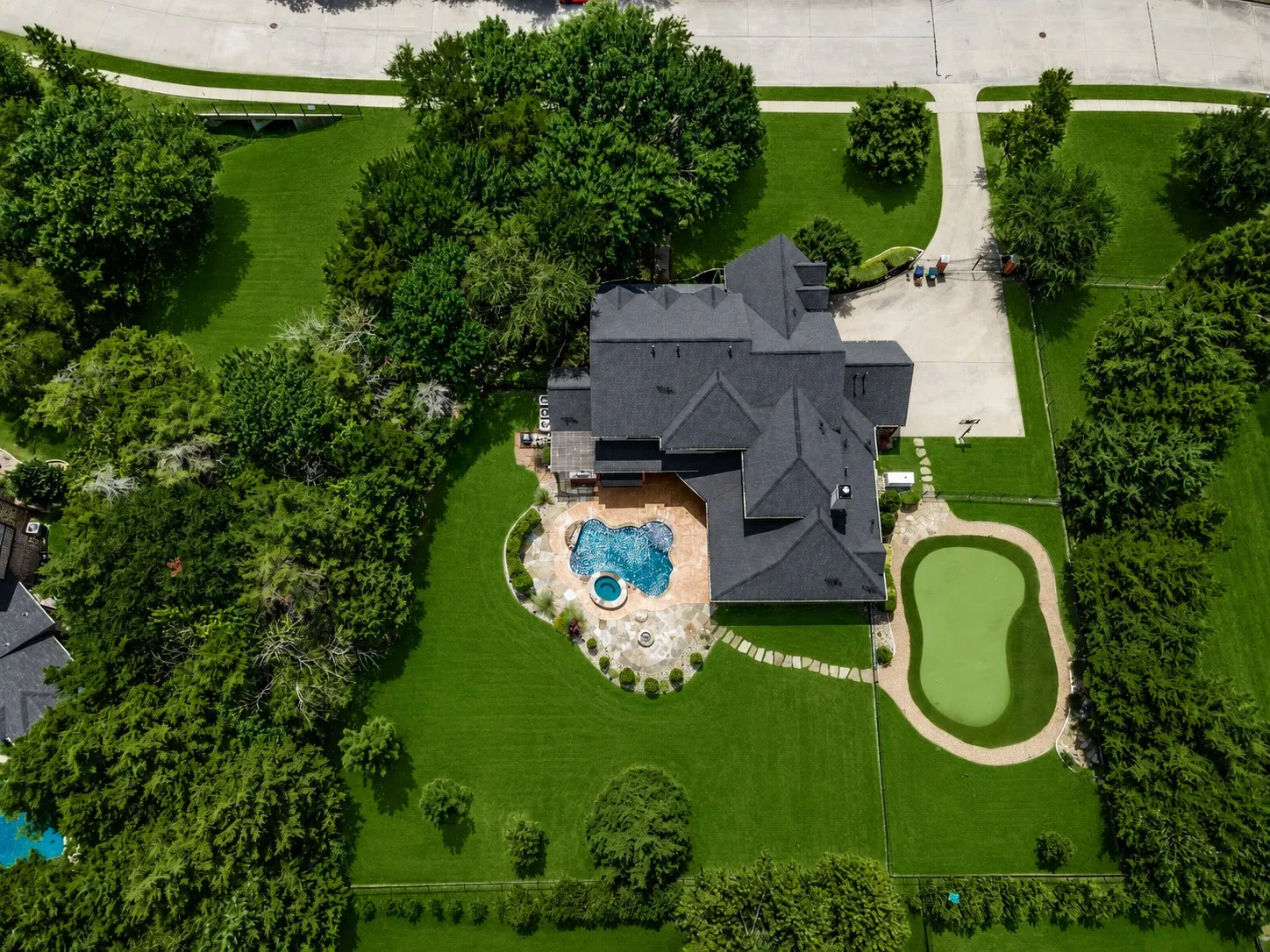 Expansive property featuring a multi-level roofline, large swimming pool with integrated spa, putting green, and a generously sized driveway