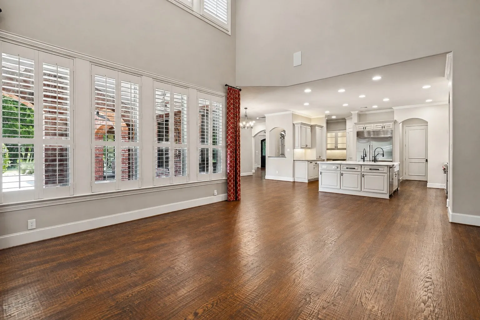 Hardwood flooring throughout, double-height ceilings, plantation shutters, recessed lighting, and a kitchen island with built-in cabinetry