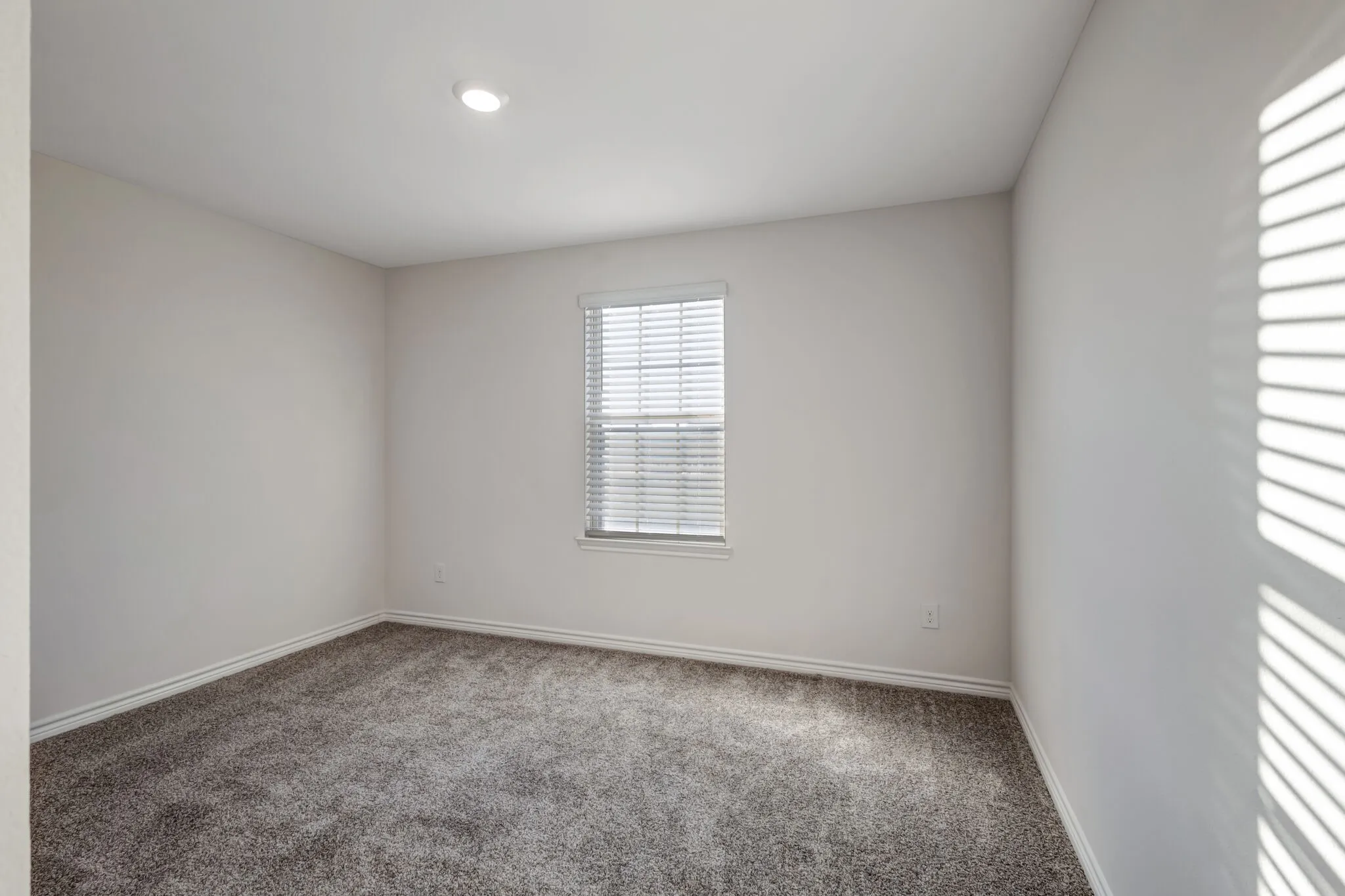 Recessed lighting, neutral wall paint, window with blinds, and carpet flooring