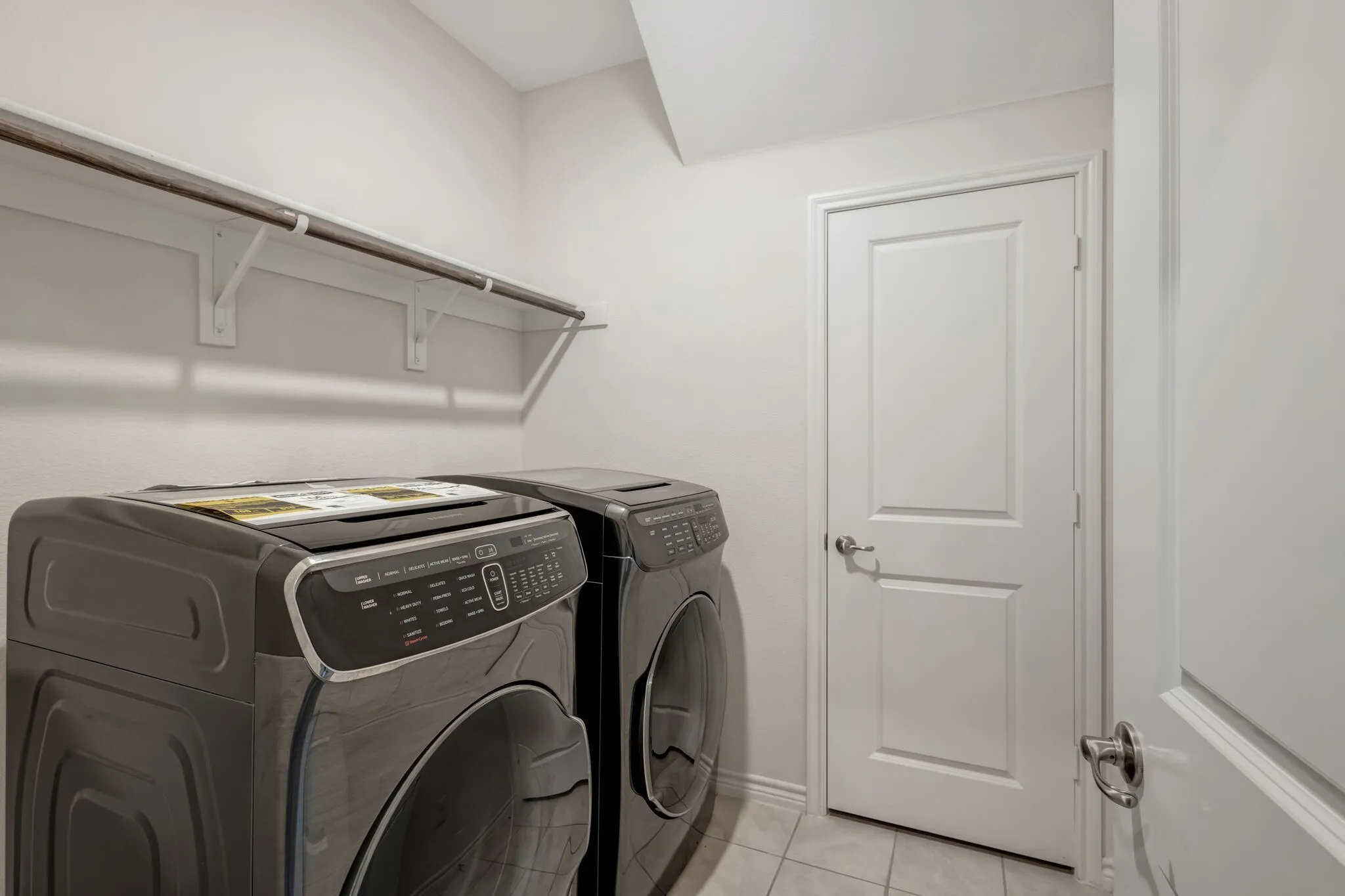 Built-in shelving with hanging rod, tile flooring, and white two-panel interior doors