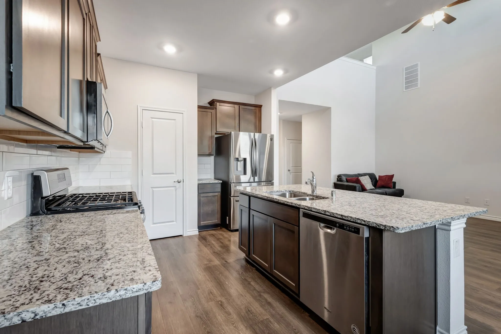 Kitchen featuring stainless steel appliances, granite countertops, subway tile backsplash, wood-finish flooring, and recessed lighting