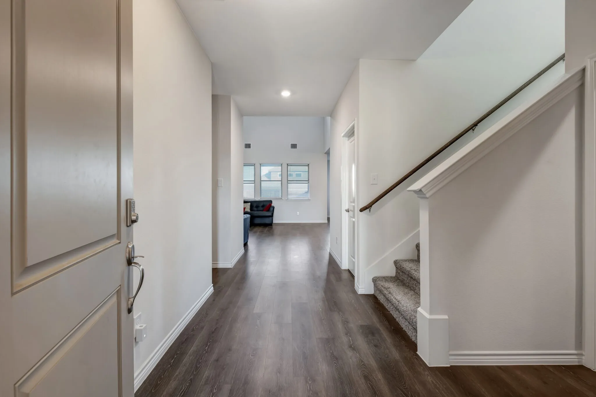 Entryway featuring wood-finish flooring, white walls, and a staircase with carpeted treads