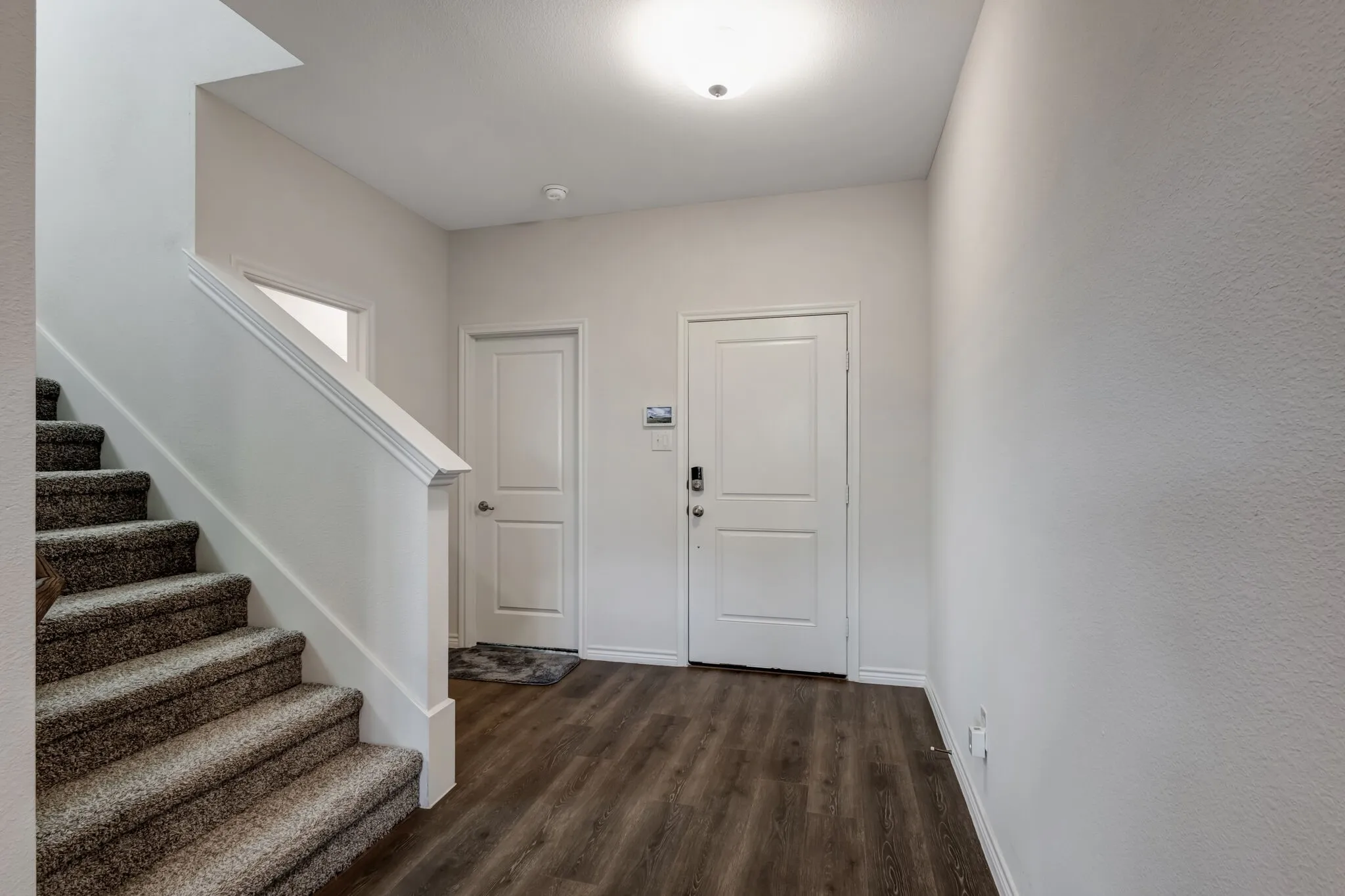 Entryway featuring wood-finish flooring, two panel interior doors, and a staircase with carpeted treads