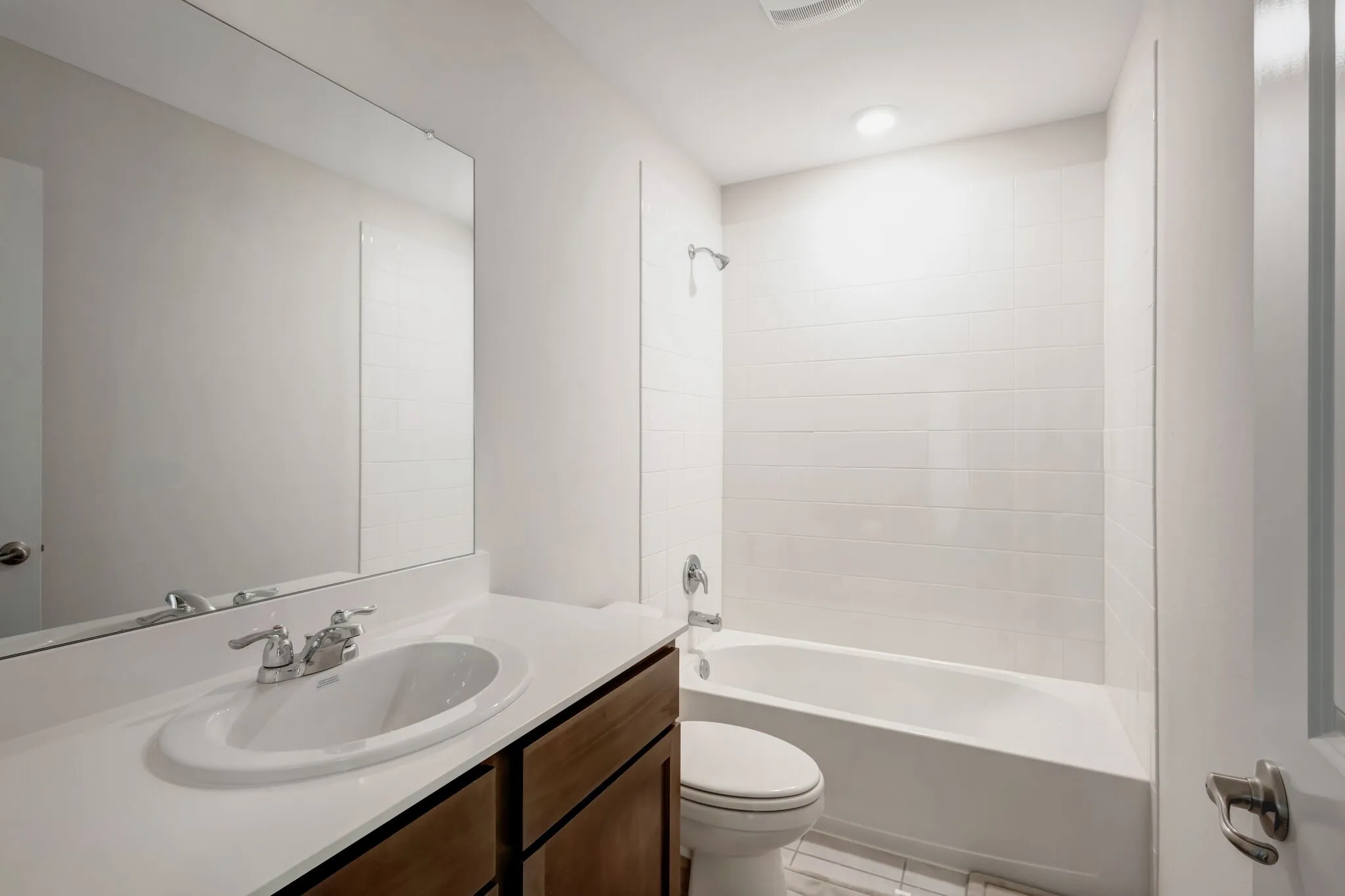 Bathroom featuring a single vanity with an integrated sink, polished chrome faucet, and a large wall-mounted mirror