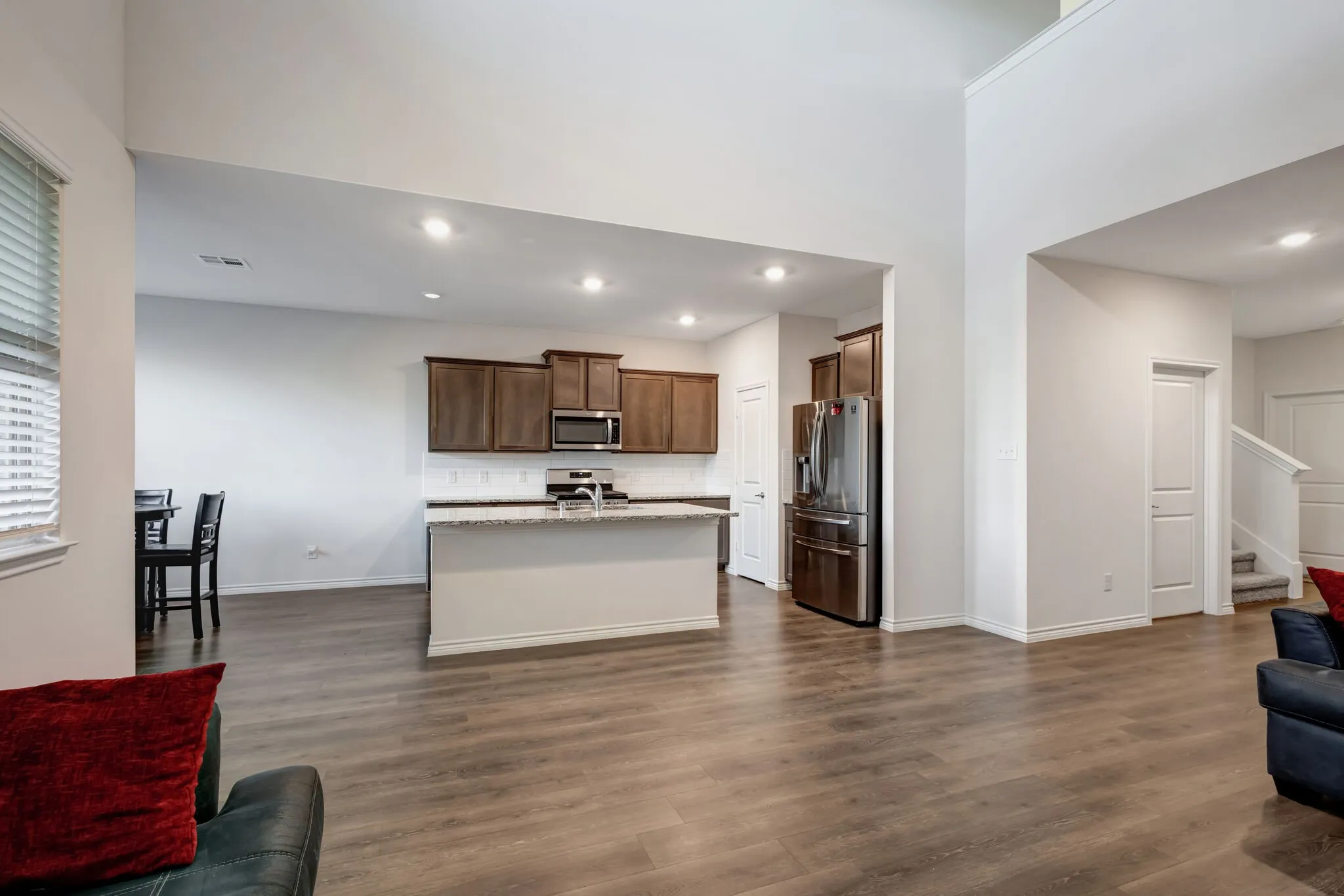 Open-concept living space with wood-finish flooring, vaulted ceilings, and recessed lighting