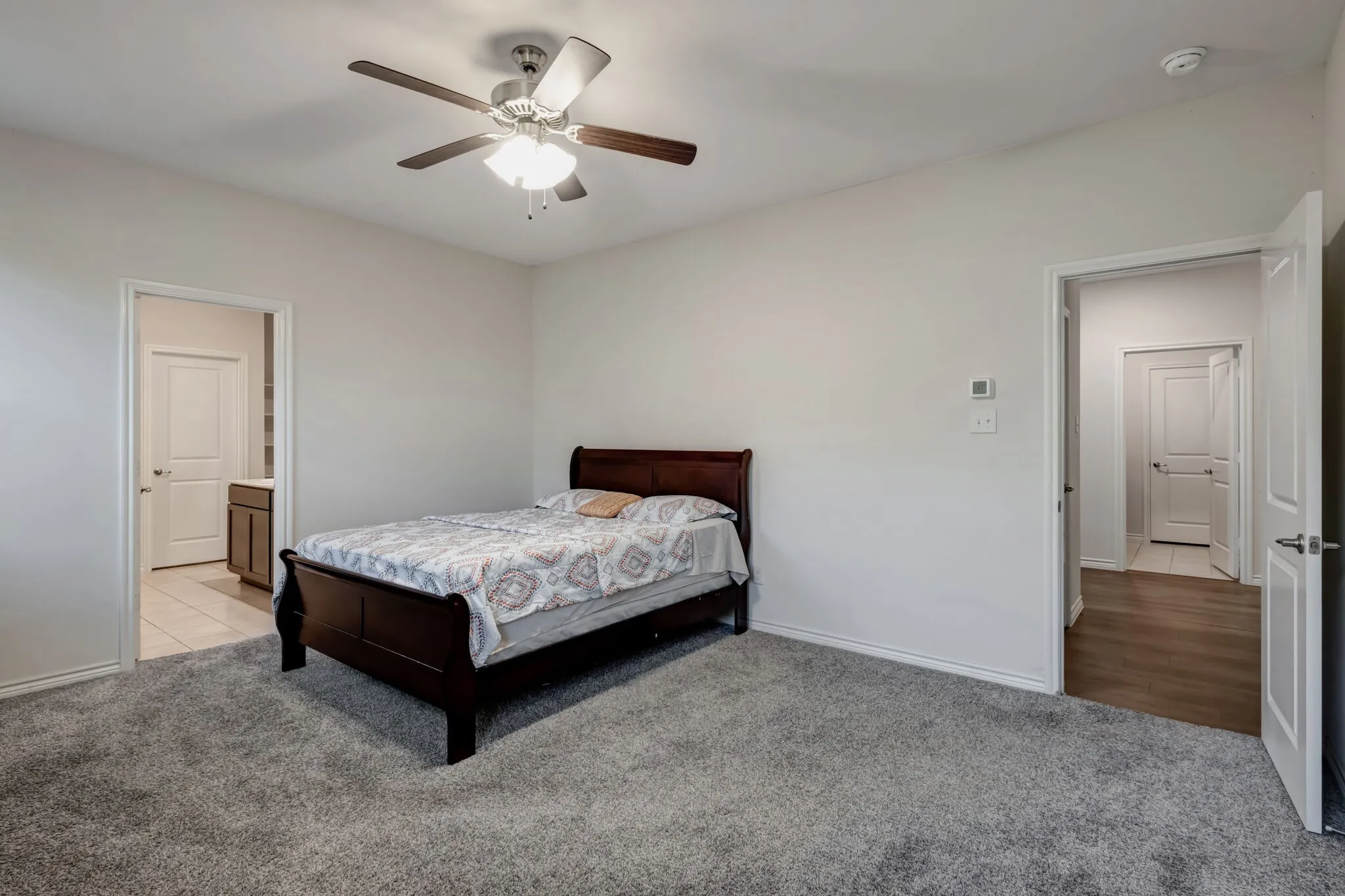Expansive room featuring plush gray carpeting, a ceiling fan with integrated lighting, and neutral wall tones
