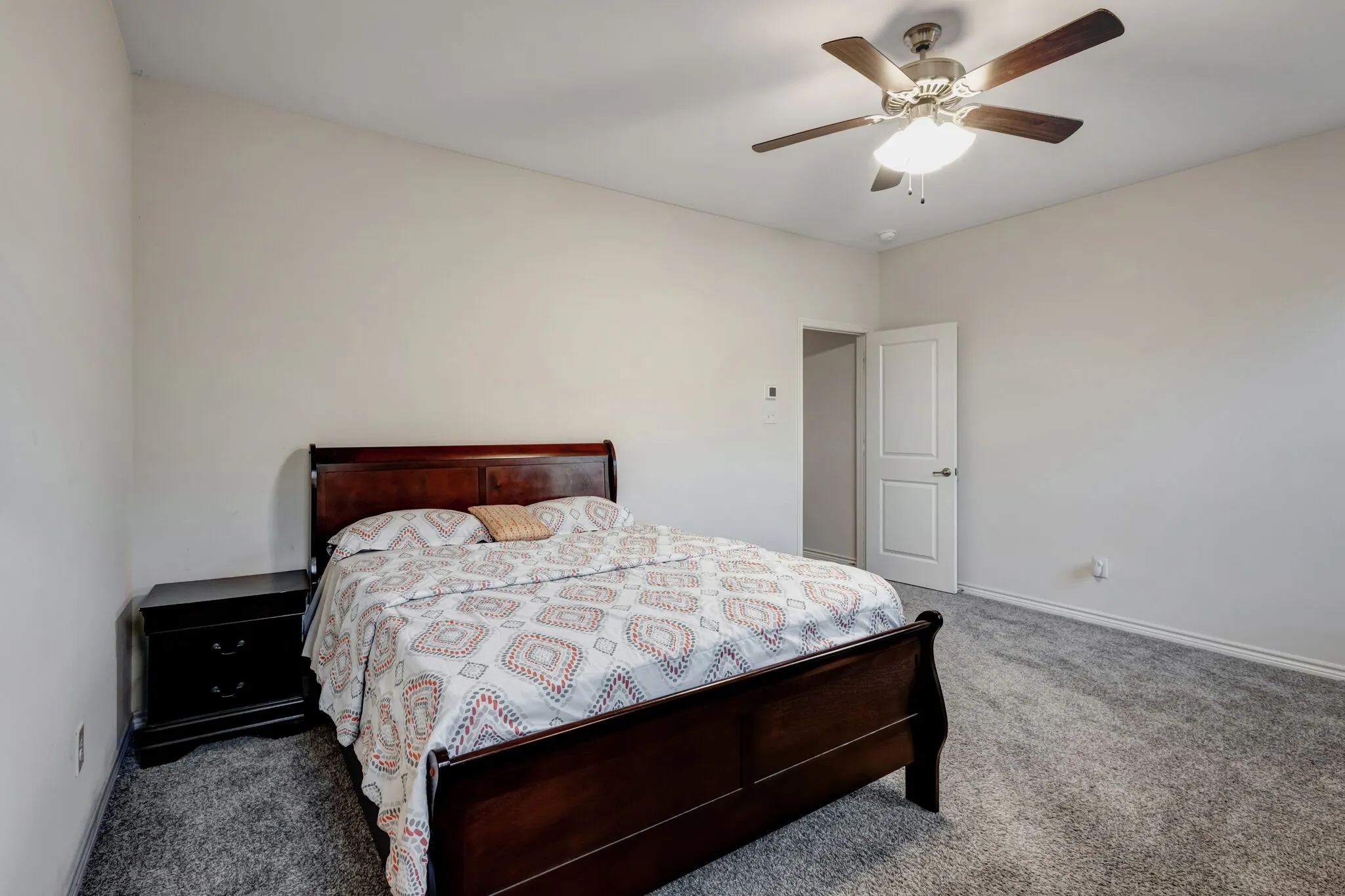Neutral wall color, plush gray carpeting, and a ceiling fan with integrated lighting