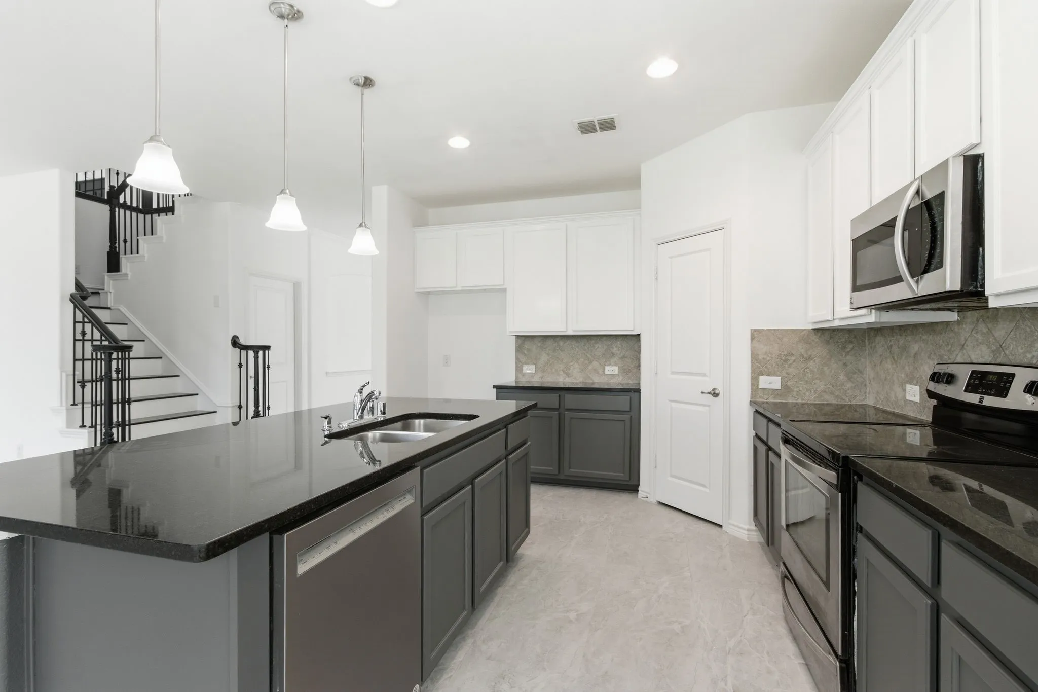 Kitchen featuring dark cabinetry, light upper cabinetry, stainless steel appliances, dark countertops, and a gray-patterned backsplash