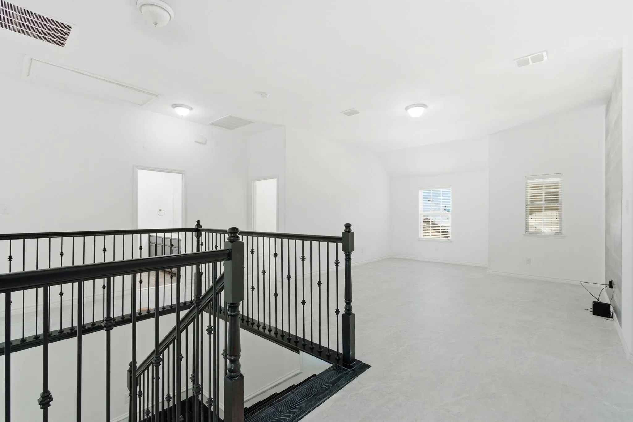 Spacious upper-level landing with iron balusters, light-toned carpeting, recessed lighting, and multiple windows
